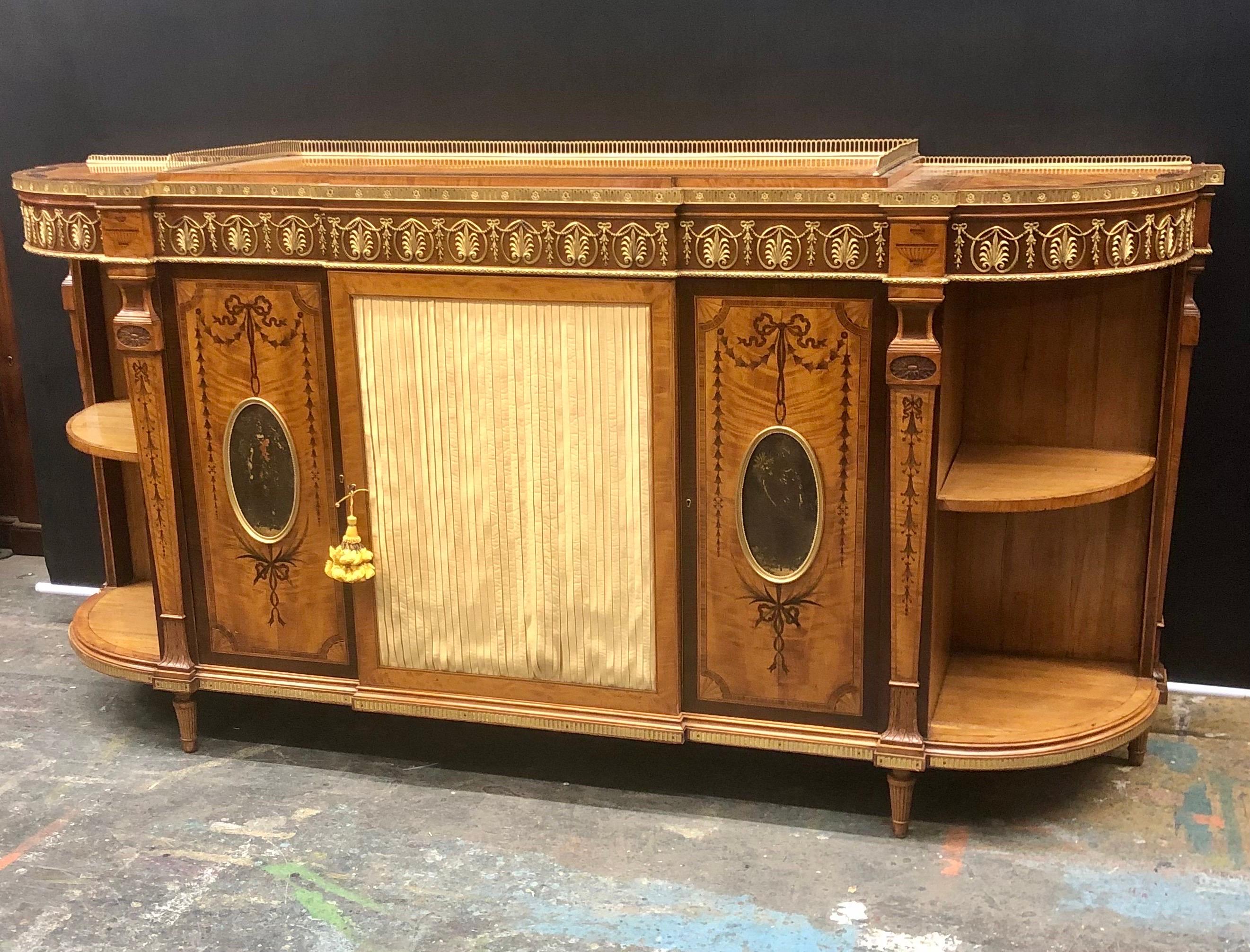The Royal furniture-makers, Wright and Mansfield of London were the Cabinet Makers for this rare Adam Style Satinwood Ormolu Mounted Credenza or Side Cabinet. This Regal Satinwood Cabinet has an elevated center stage top with four Fan Cartouche