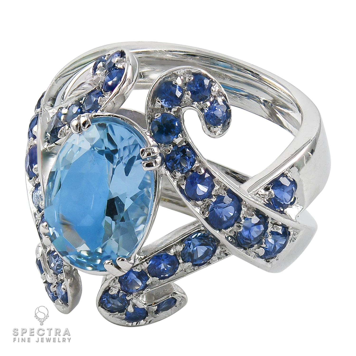 Te presentamos el impresionante Anillo de Diamantes Zafiro Aguamarina, una fusión de elegancia y asequibilidad de Adamas. Imagina contemplar una serena aguamarina ovalada, enclavada en medio de un coro de vibrantes zafiros azules y centelleantes