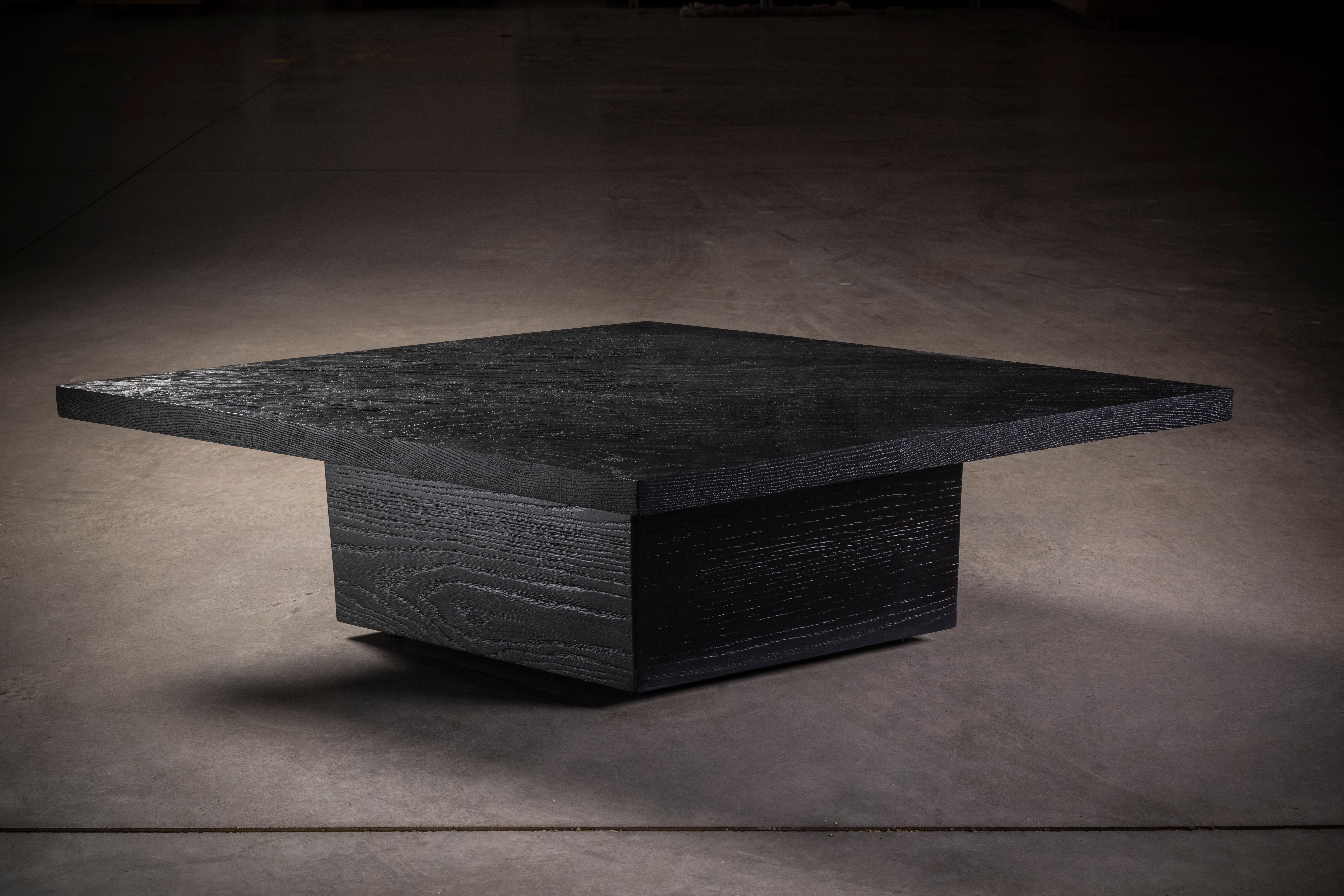 Massiver Esstisch aus schwarzer Eiche mit rautenförmiger Tischplatte und Sockel.


