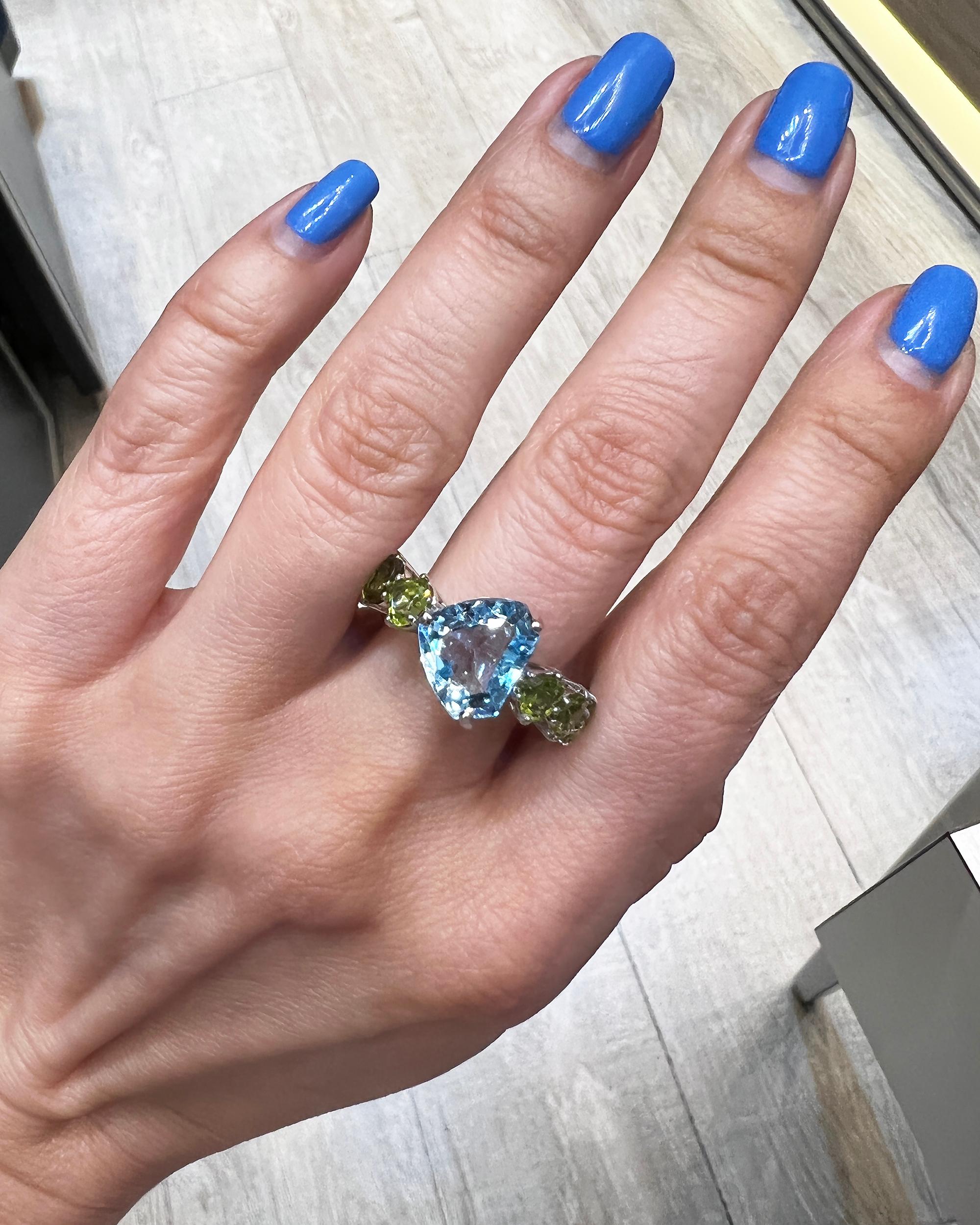 Creating an illusion of an eternity ring with stones seeming to flow around the entire band, the exceptionally bold and fun cocktail ring made in Italy in the 21st century, 2018, is crafted in 18K white gold and features a vibrant blue topaz