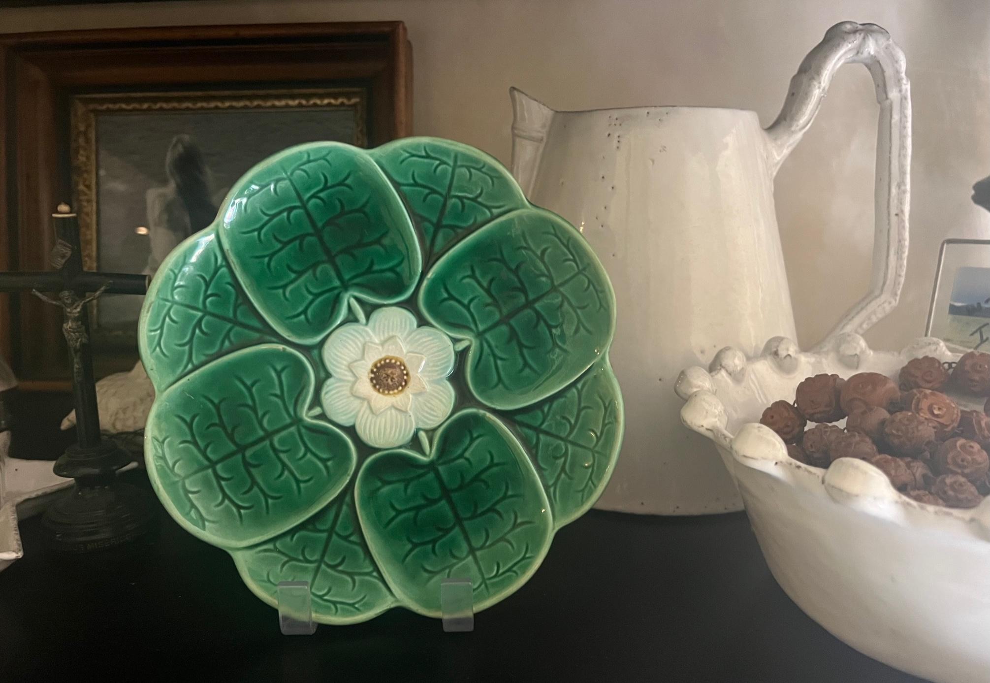 Antique majolica made by Adams and Bromley in the late 19th century. The plate has vibrant green leaves surrounding a central white flower with faint hints of blue.

This is the smaller of the two Adams & Bromley plates in the same pattern, one is