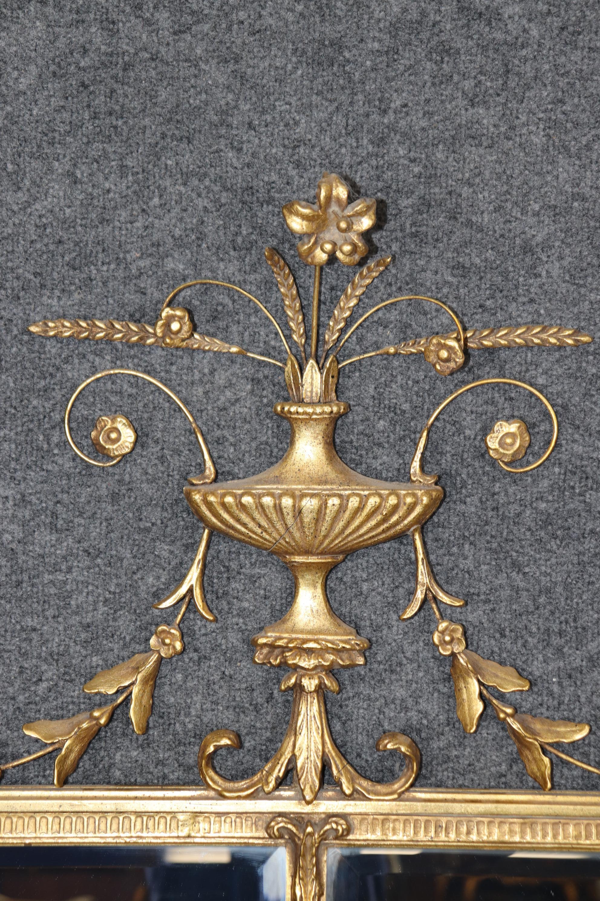This is a fine quality Friedman brothers mirror with beveled mirrored panels and gorgeous gold leaf decorated details of flowers on wire arimitures and carved details in the Adams style. Measures 64.5 tall x 41 wide x 4 inches deep. In very good