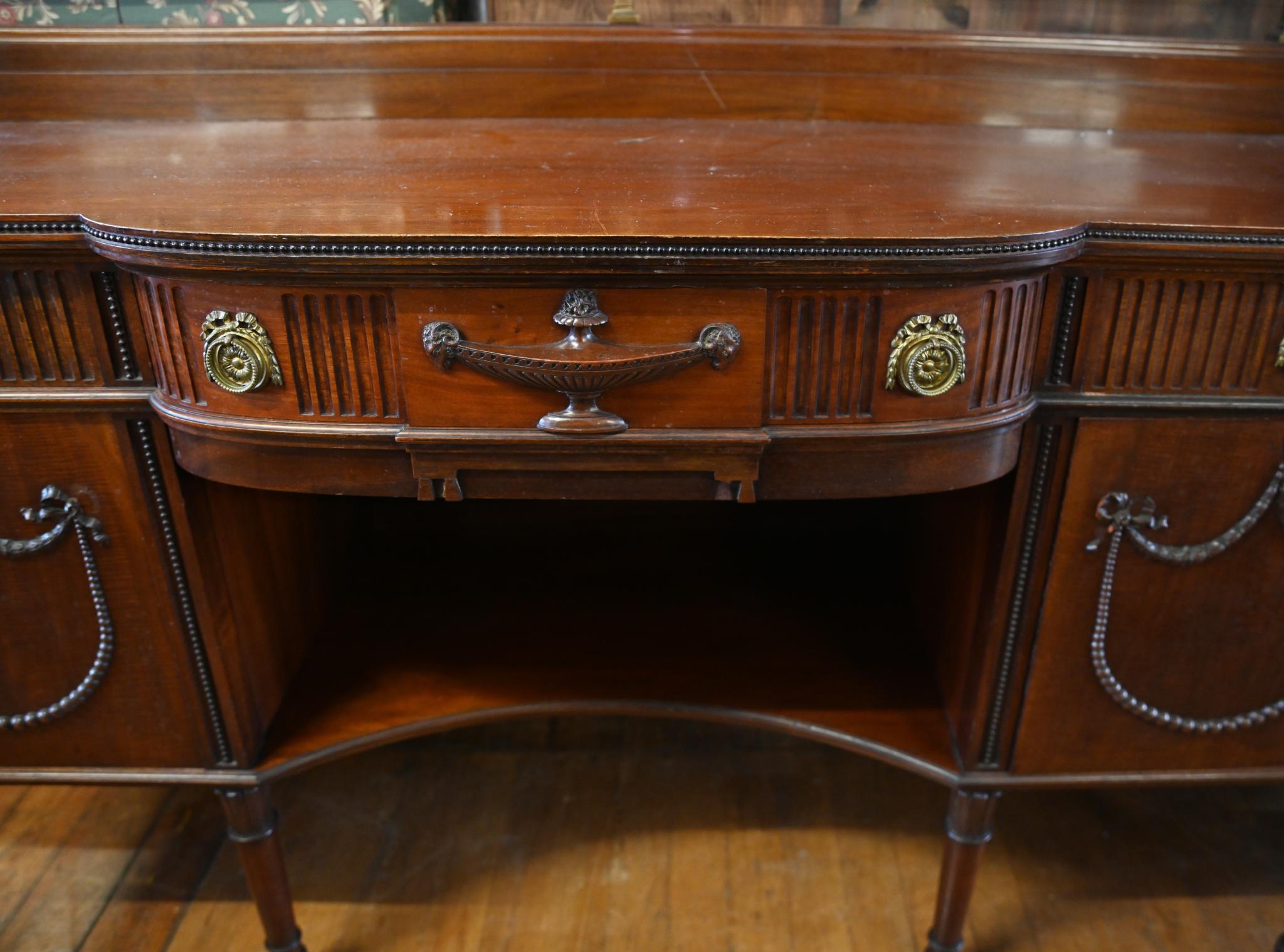 Refined Adams style sideboard with a brass back rail mahogany
Circa 1880
Features classic Adams motifs like the wide urn and draped festoons and sashes
Big piece so plenty of storage
Bought from a private house sale in London's Queens Park
We ship