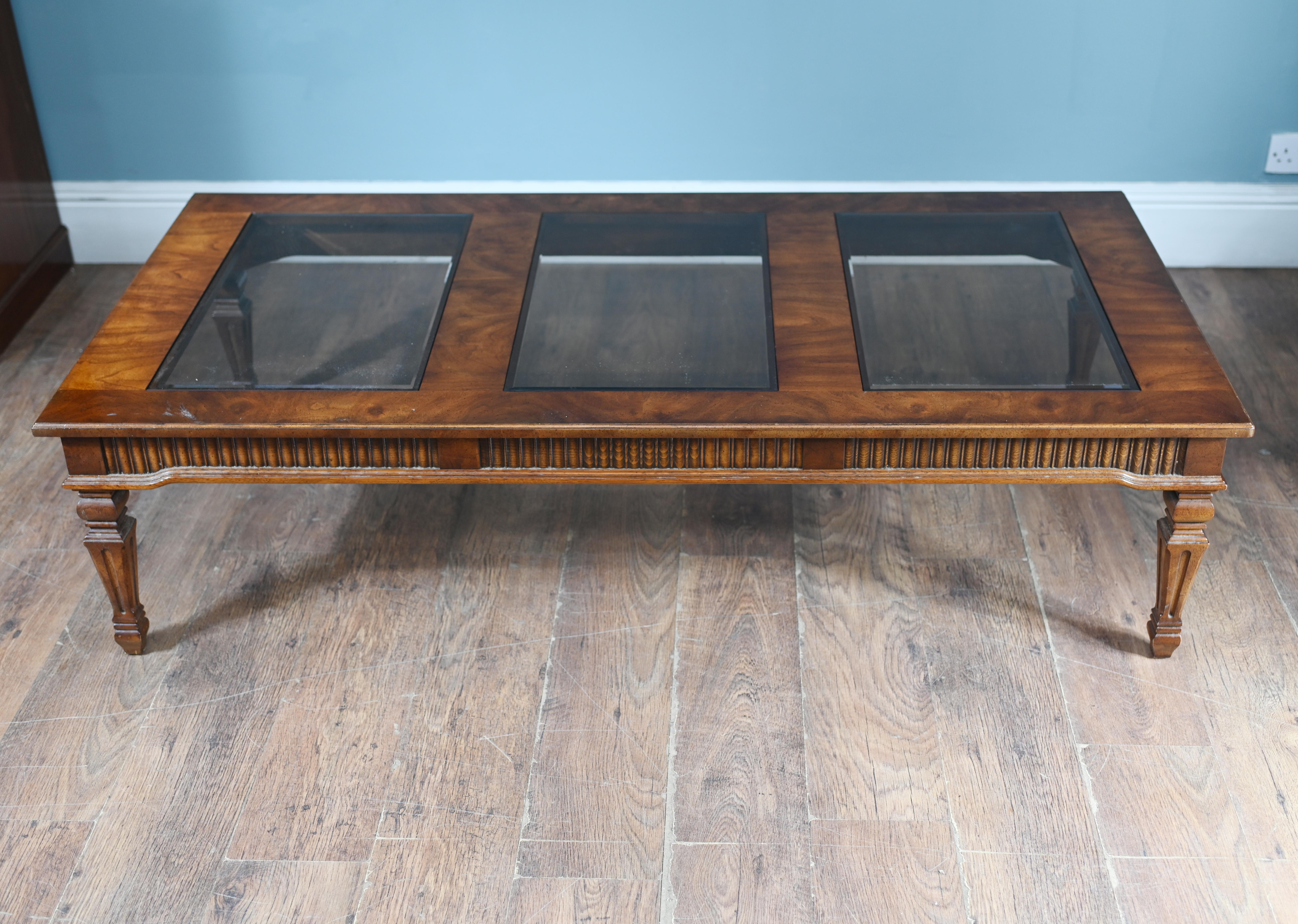 You are viewing a refined walnut coffee table in the Adams Revival style
Top features four glass bevelled edge panels
Great neo classical look to coffee table
Top: The tabletop features three rectangular glass inset panels,
framed in warm-toned wood