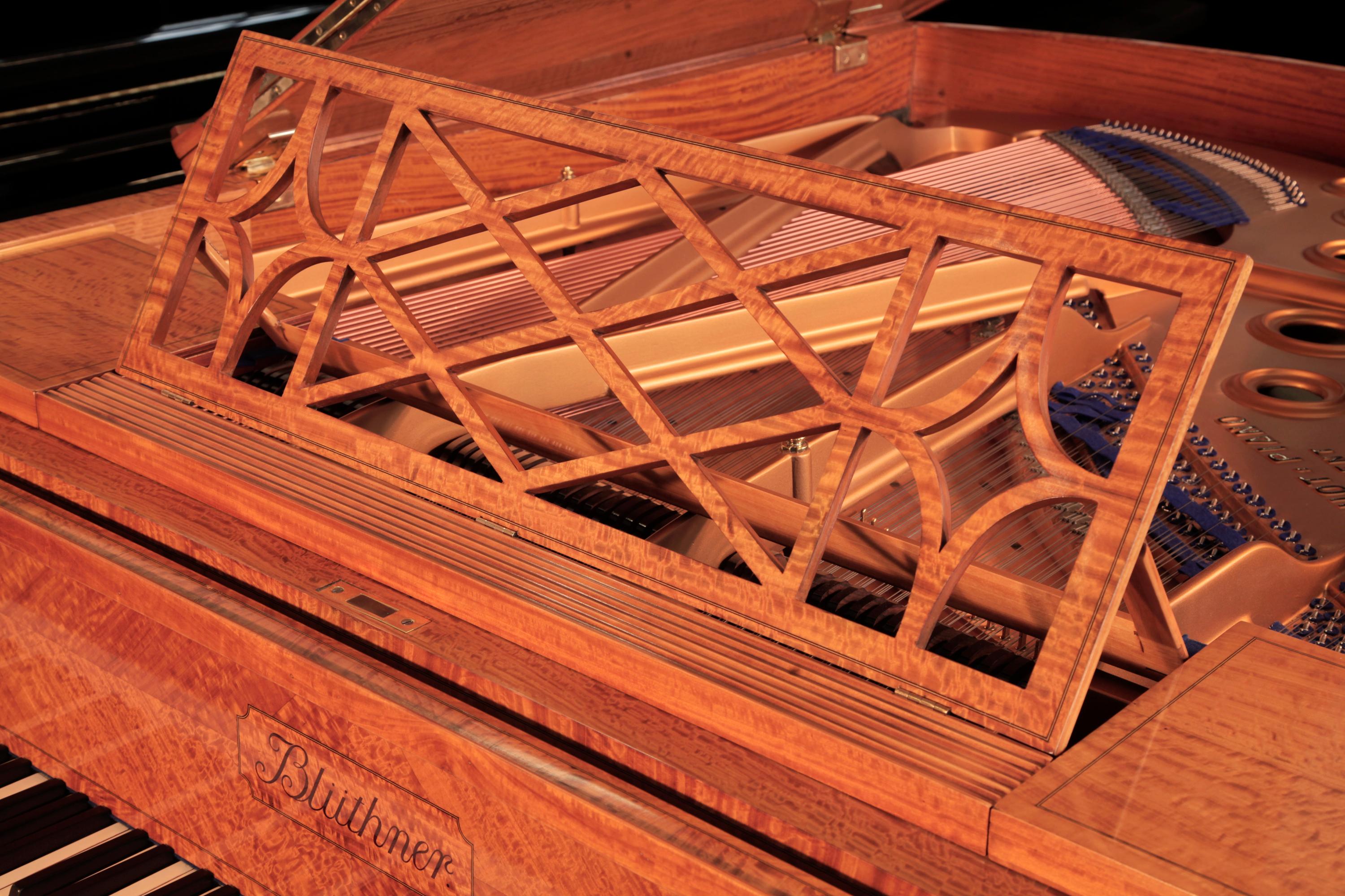 Piano à queue Bluthner de style Adams, 1911, avec caisse en satin poli à la française, en quart de coupe, avec incrustation de cordes en buis et accents de bandes transversales. Le placage de bois satiné de l'armoire en fait une pièce d'exception.