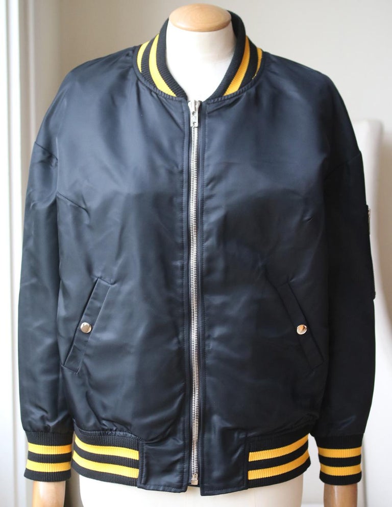 Adaptation's black tech-satin bomber jacket is appliquéd at the back with yellow and white embroidered California patch. 
Lined jacket with rib-knit stand collar, cuffs, bottom and§ angled side pockets. 
Black tech-satin. 
Snap-front closure. 
100%