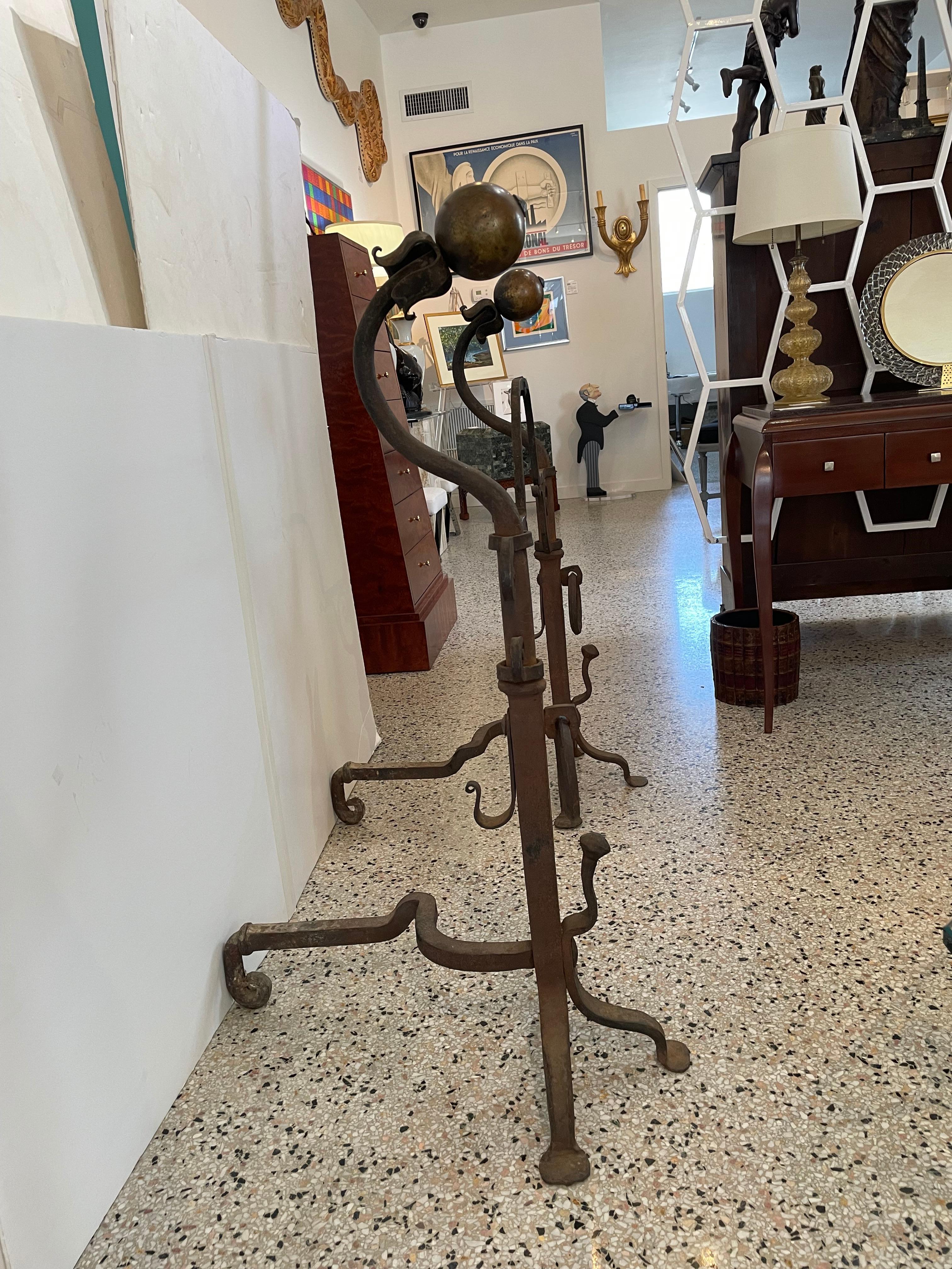 This large scale set of andirons are very much in the manner of Spanish Colonial pieces created in the 1920s by the Palm Beach architect Addison Mizner.