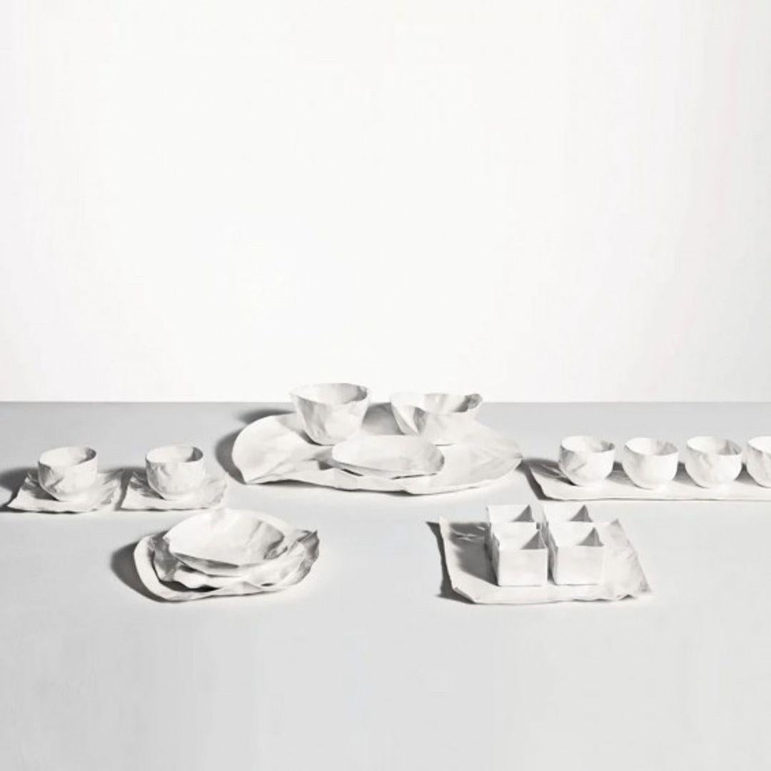 A table set in white Bone China porcelain designed by the artist and designer Xie Dong who has revisited, in a poetic way, the workmanship of traditional Chinese ceramics.The porcelain is processed to obtain a very thin thickness: extremely fine,