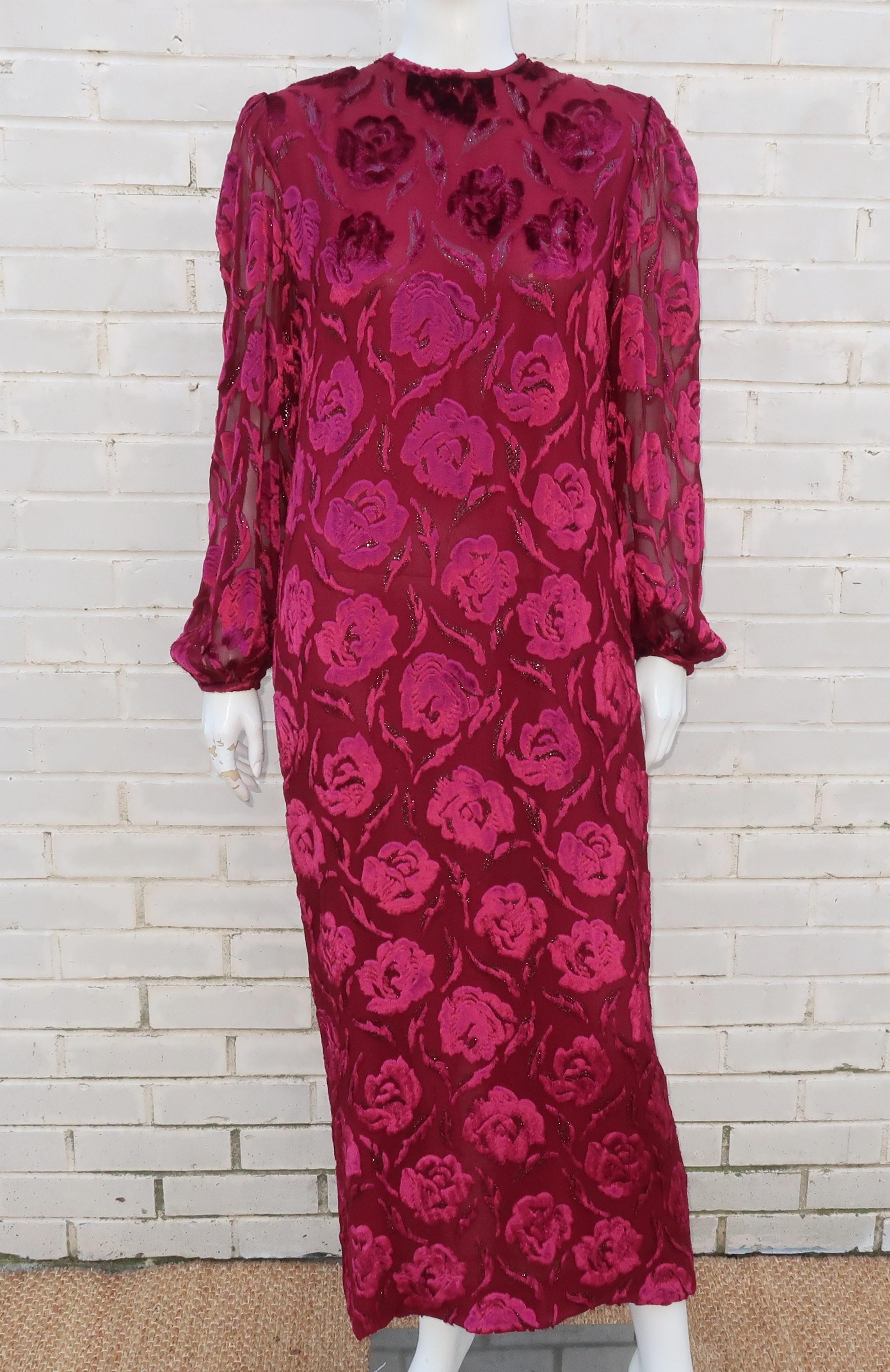 1980's Adele Simpson column dress in a lush cut silk velvet in a ruby red shade with darker shimmering metallic threading and a floral motif.  It zips and hooks at the back with soft shoulder pads, semi sheer sleeves that pool at the button cuffs