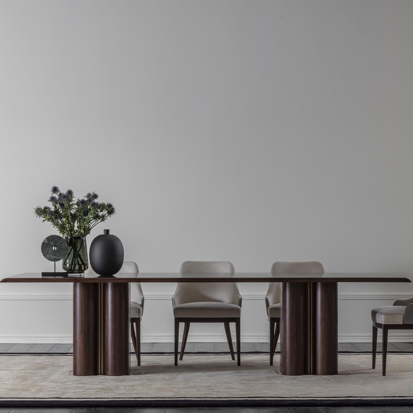Ideal to be gathered with twins around a modern table, this dining armchair exudes subtle and timeless elegance. Its walnut frame finished in matte tobacco is visible through the tapered legs, its deep hue conflicting with the off-white fabric