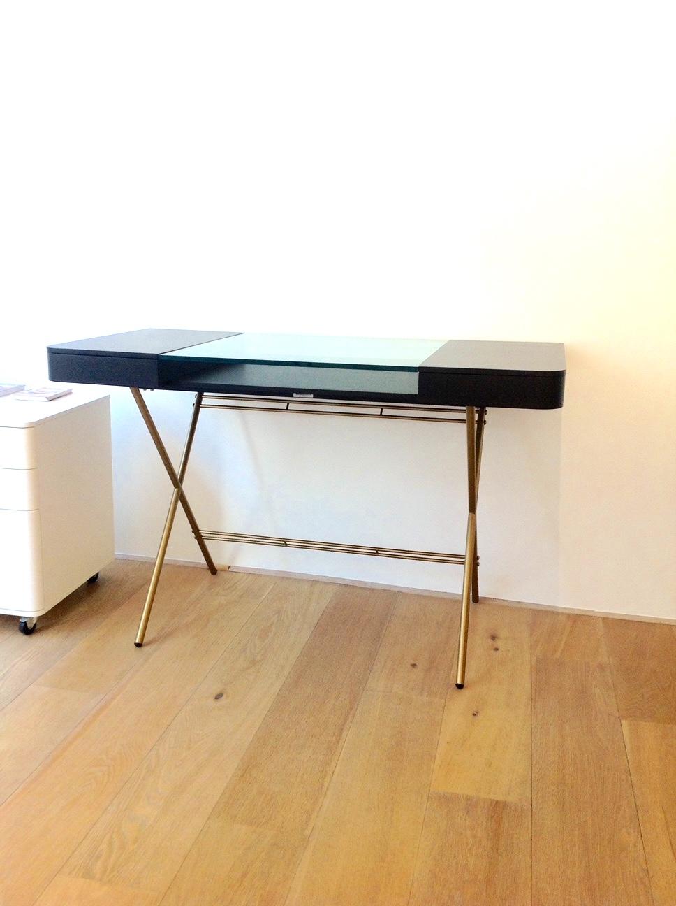 Der Schreibtisch Cosimo wurde von dem Architekten Marco Zanuso JR für die französische Luxusmöbelmarke Adentro Paris entworfen.
Der Schreibtisch besteht aus einer zentralen Klarglasplatte mit einer Ablage darunter und hat auf beiden Seiten