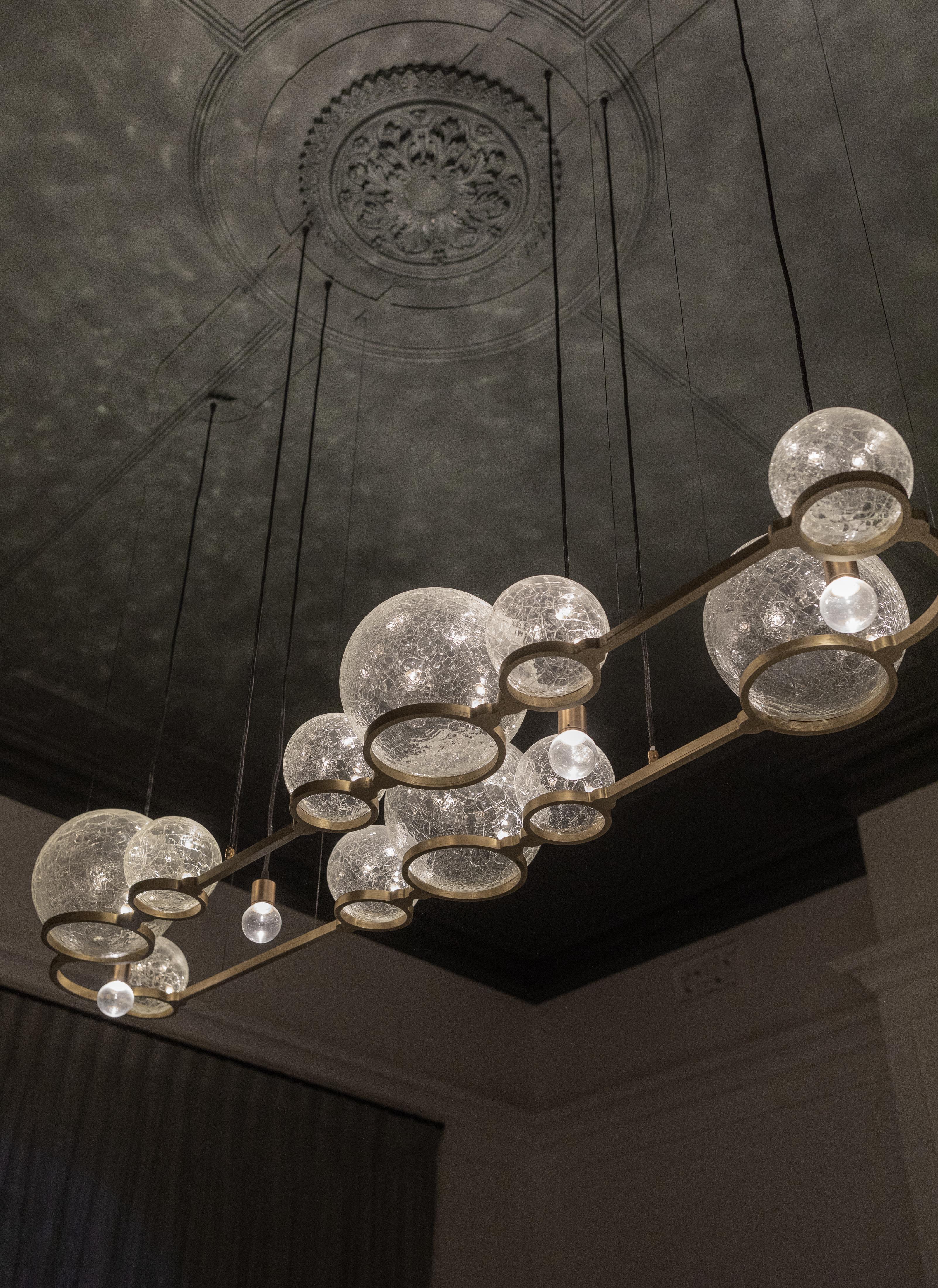 ADesignStudio Lustre Eon 11

Le lustre Eon capture l'essence du soufflage de bulles, un moment cher aux enfants. Nos sphères Crackle Eon imitent l'action d'attraper des bulles en plein vol. Ces sphères sont disposées en grappe asymétrique, le verre