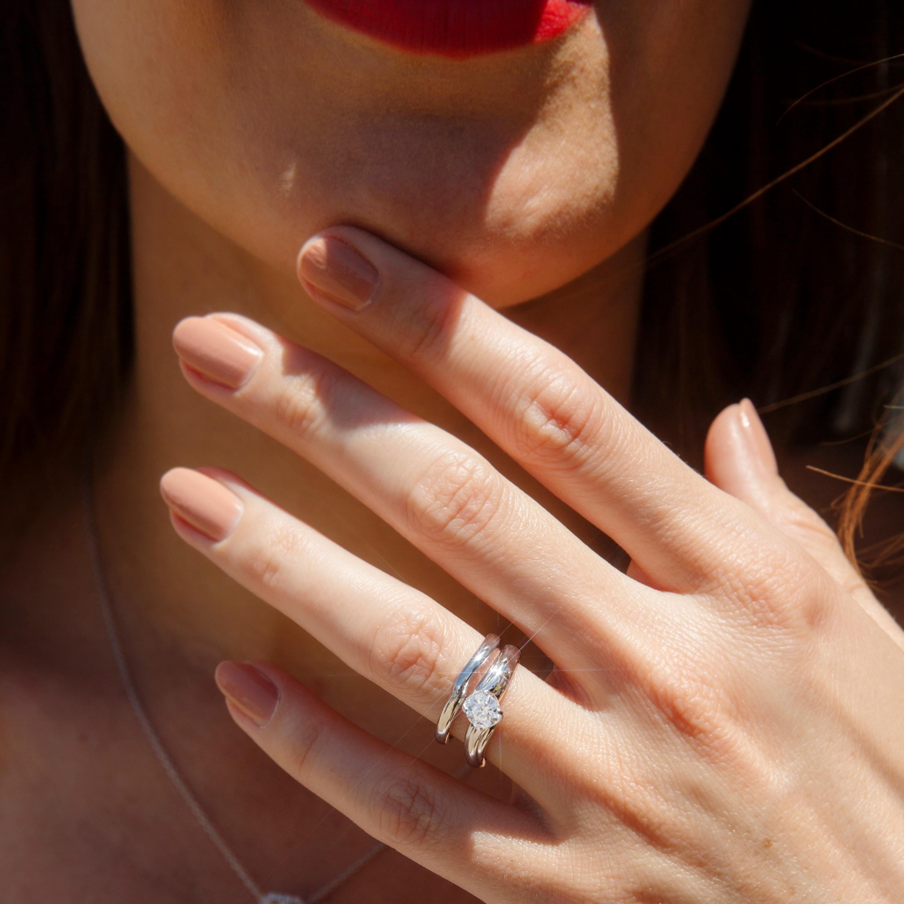 Forged in 18 carat white gold, this gorgeous bridal set features an engagement ring with a captivating ADGL certified 0.51 carat round brilliant cut diamond wrapped between grooved crossover shoulders and an elegant high polish wedding band with