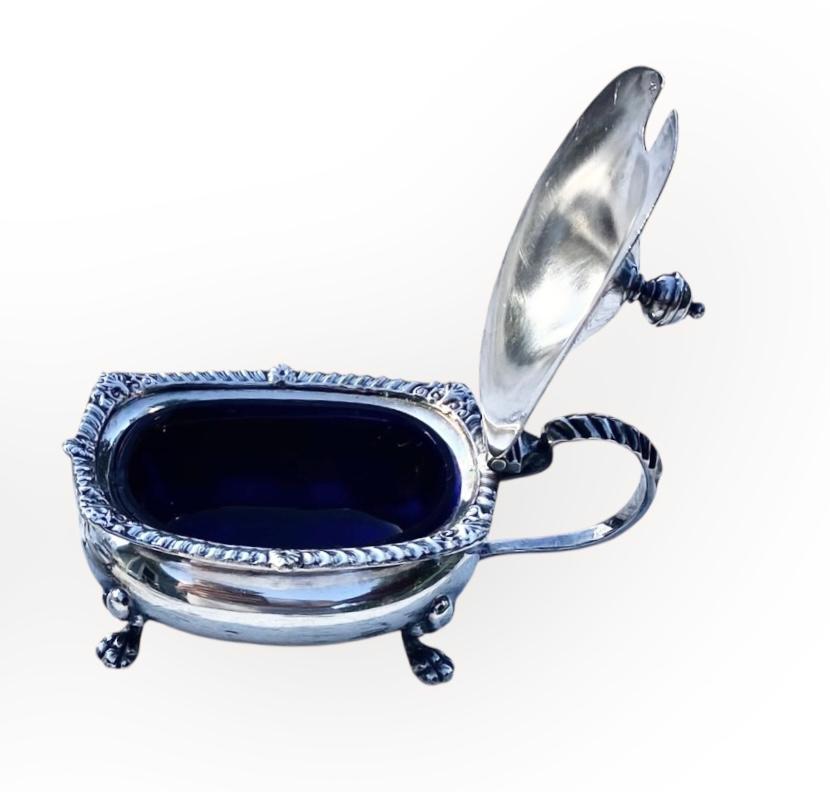 Saleros antiguos Adie Brothers Silver Plate con tapas abatibles y revestimientos originales de cristal de cobalto. De estilo rococó, con patas de león, delicados remates, motivos rocaille, roleos y diseños naturalistas inspirados en plantas y