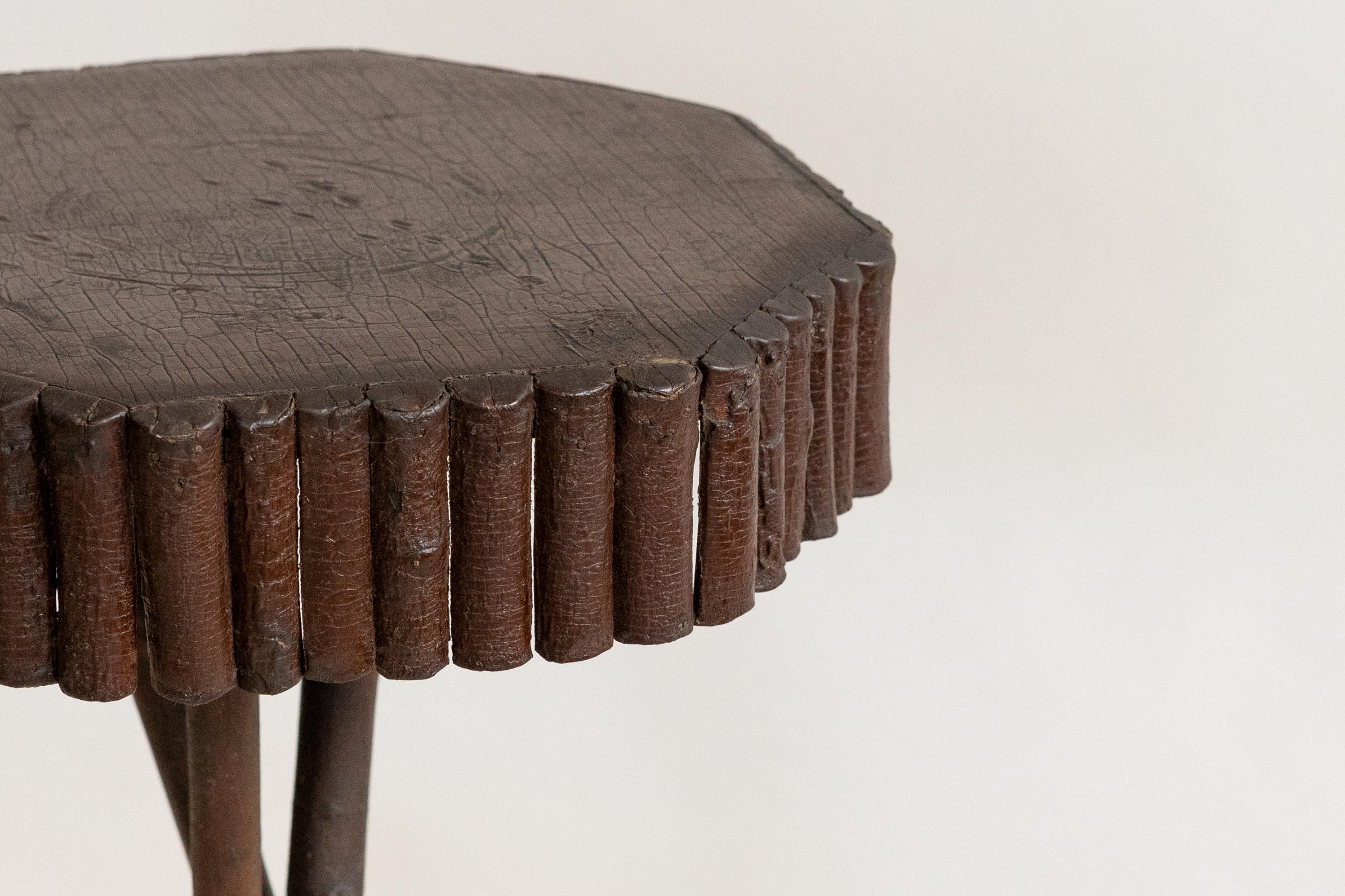 États-Unis, vers 1920. Une charmante table d'appoint ou support de plantes de style Adirondack, faite à la main. Construction en bois avec un plateau octogonal soutenu par trois pieds. Façonnée à partir de branches recouvertes d'écorce et peinte en