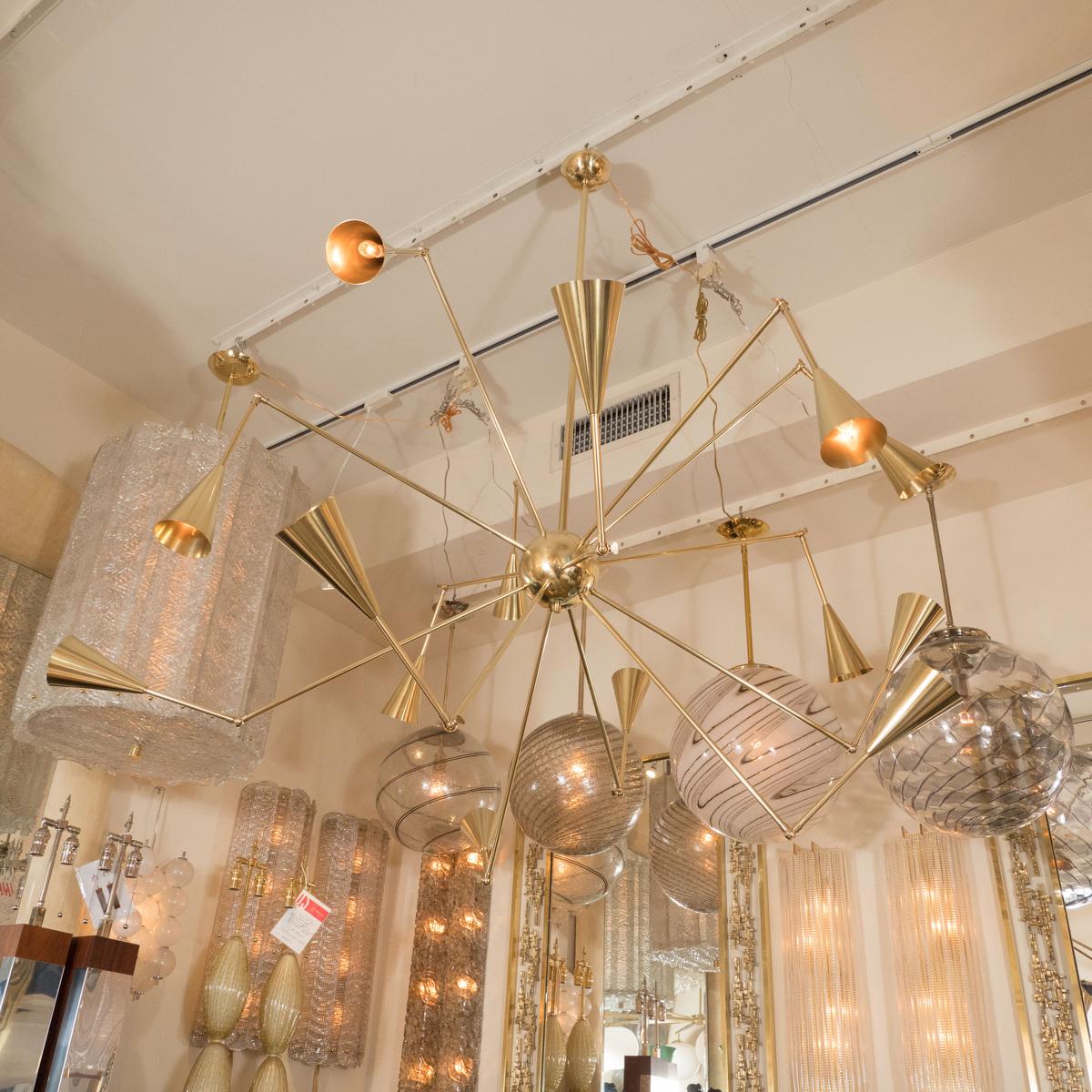 Adjustable arm brass chandelier with fourteen conical shades. Measured as shown.