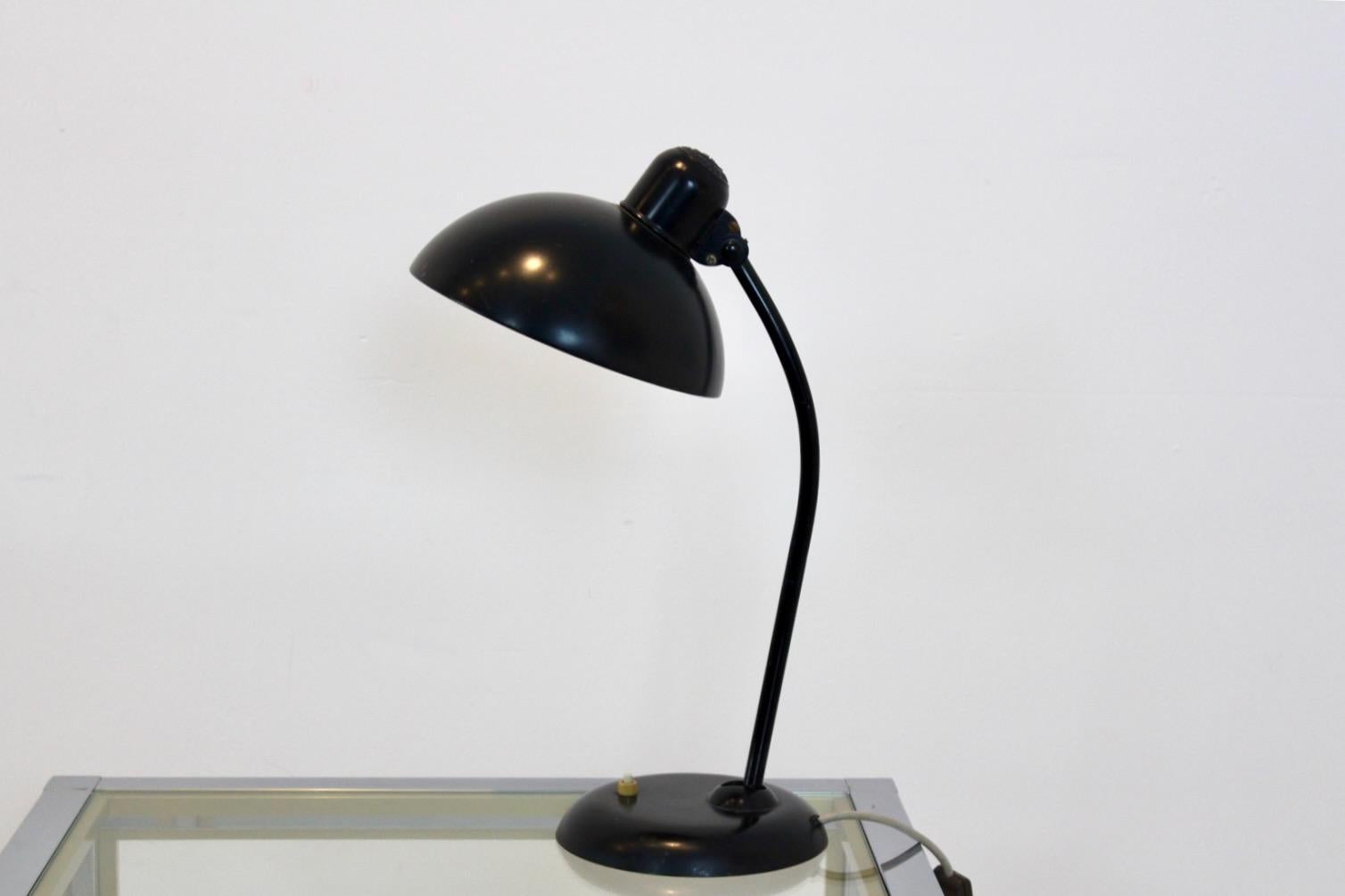Preciosa lámpara de escritorio alemana fabricada por Kaiser Idell y diseñada por Christian Dell en la década de 1930.  Con vástago de acero tubular inclinado y arqueado, y pantalla de cúpula metálica lacada en negro, ancha y ajustable. Utiliza un