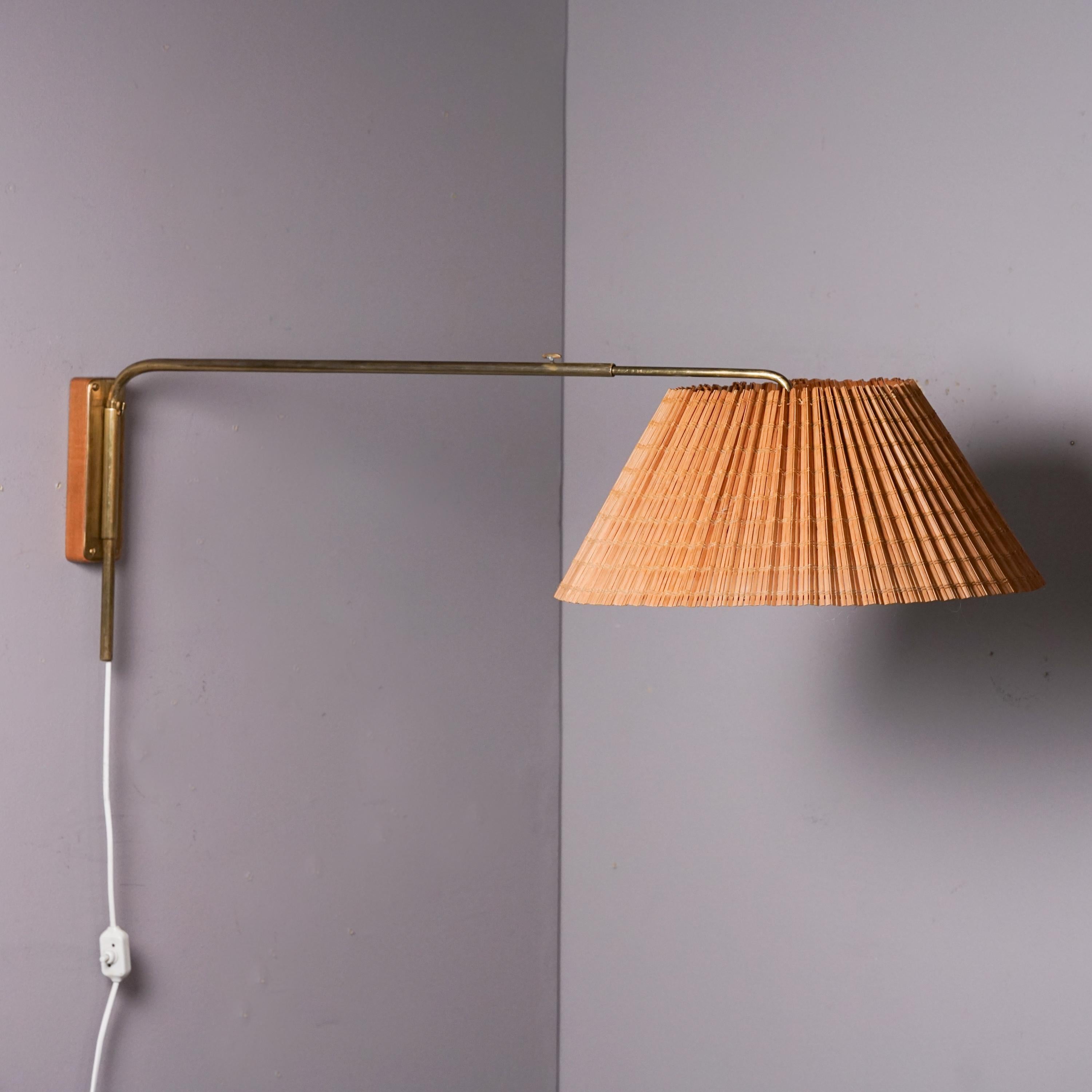 Adjustable wall light, manufactured in Finland, 1950s. Brass frame with wood slat shade and teak detail. The depth of the light is adjustable between 100-125 cm. Good vintage condition, minor patina and wear consistent with age and use.  