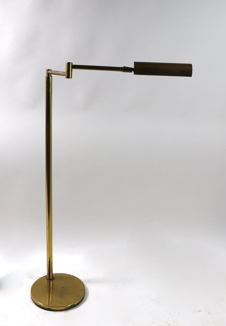 Adjustable brass floor lamp by Koch & Lowy. This example has a swing out arm, which hold a tilting brass hood shade (8 inch). Arm in folded position 18 inch L x 25.5 inch L when extended. The lamp also is adjustable in height Low position 40 inch x
