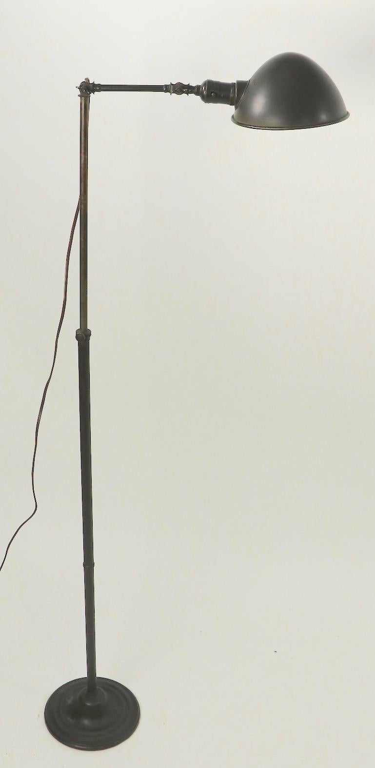 Very nice Industrial style brass floor lamp, in very good original and working condition. This lamp is adjustable in height 35 in. Lowest position x 60 in. Highest position, the arm is 16 in L, Base 8 in. dia. and the hood shade can be tipped to