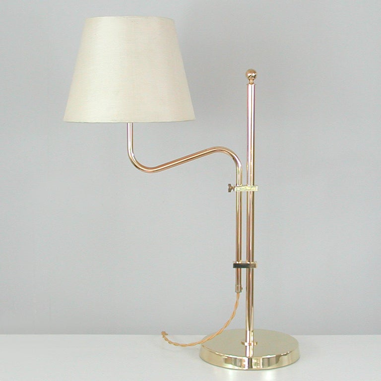 This unusual mid-century table lamp was designed and manufactured in Sweden in the 1950s by Bergboms (model no. B-132). It features a brass base with height adjustable and articulating brass lamp arm and cream colored fabric (silk) lampshade.