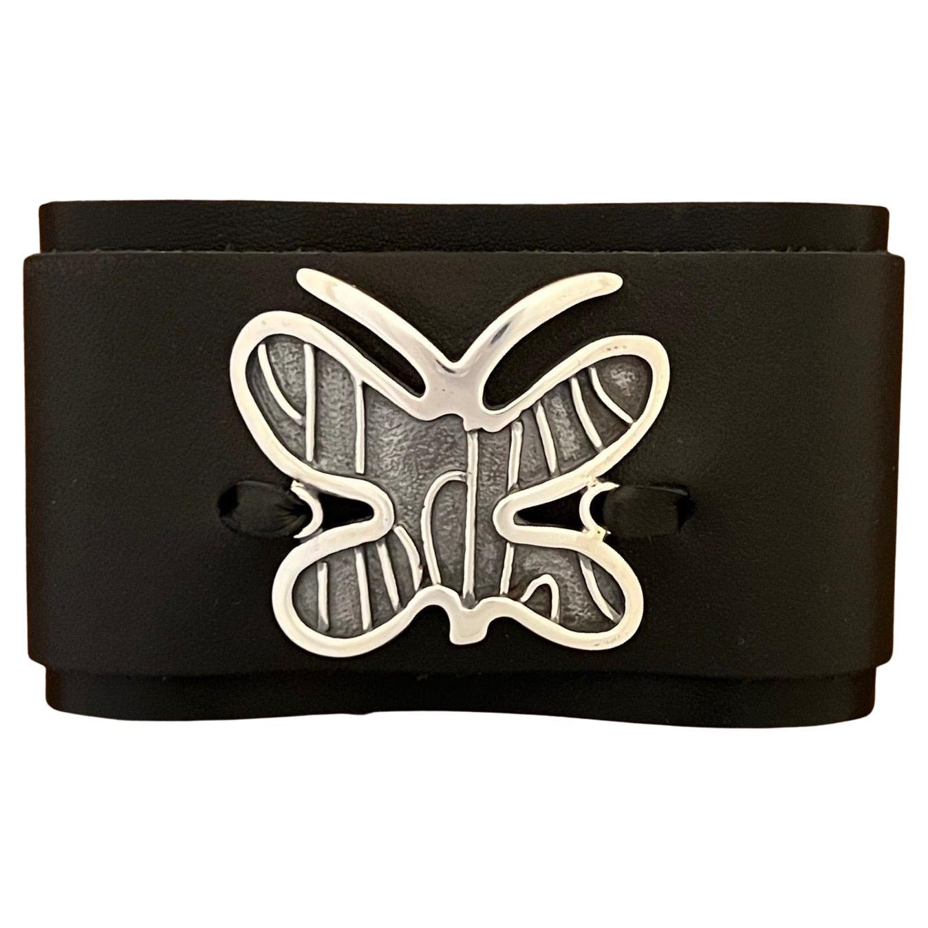 Adjustable Butterfly leather cuff by Melanie Yazzie black silver

Melanie A. Yazzie (Navajo-Diné) is a highly regarded multimedia artist known for her printmaking, paintings, sculpture, and jewelry designs. She has exhibited, lectured, and taught