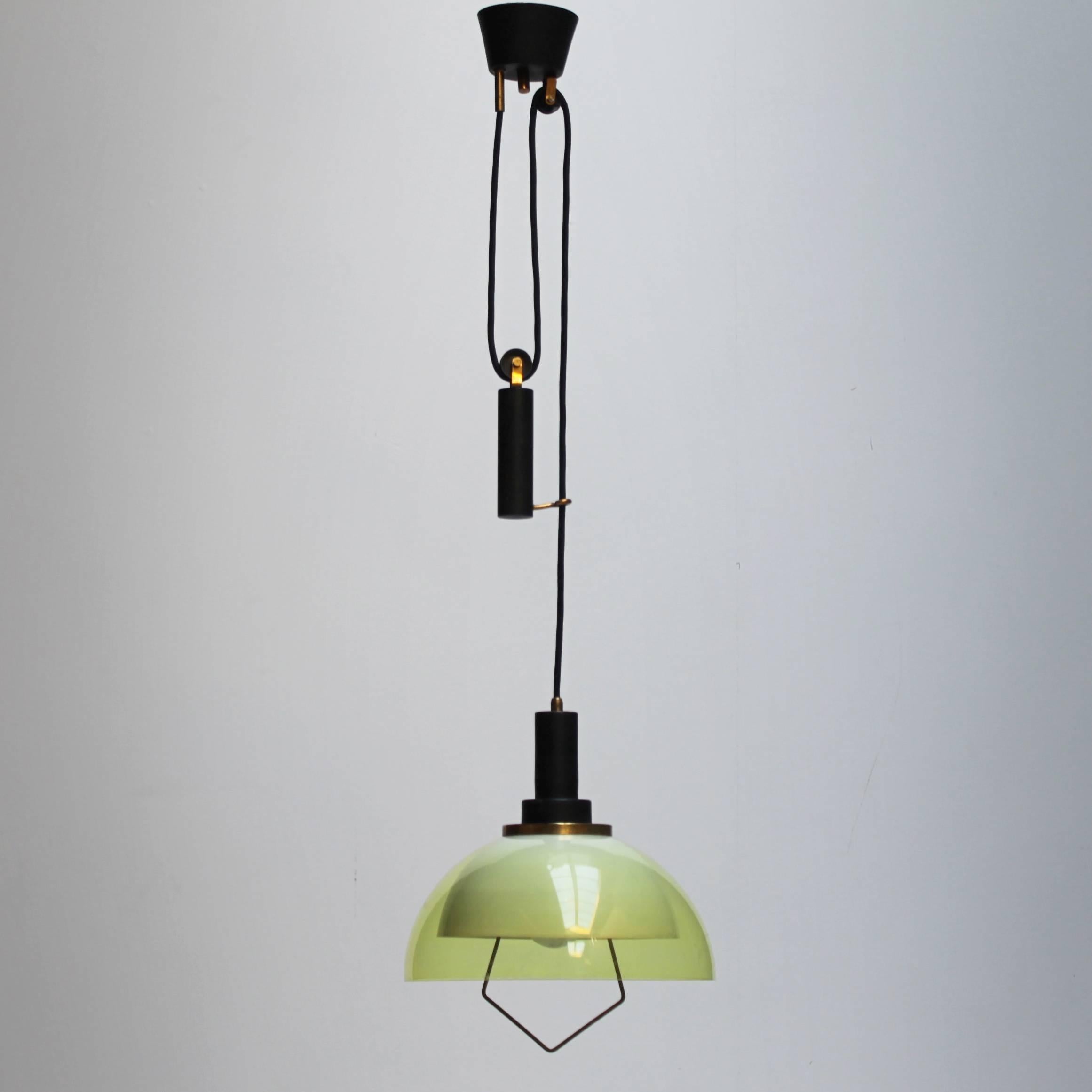Pendant by Stilux Italy from the 1950s. This pendant, which can be adjusted in height with a counterweight, shows a striking combination of brass, black enameled metal and green/yellow plastics. Inside a white metal shade and outside an extra