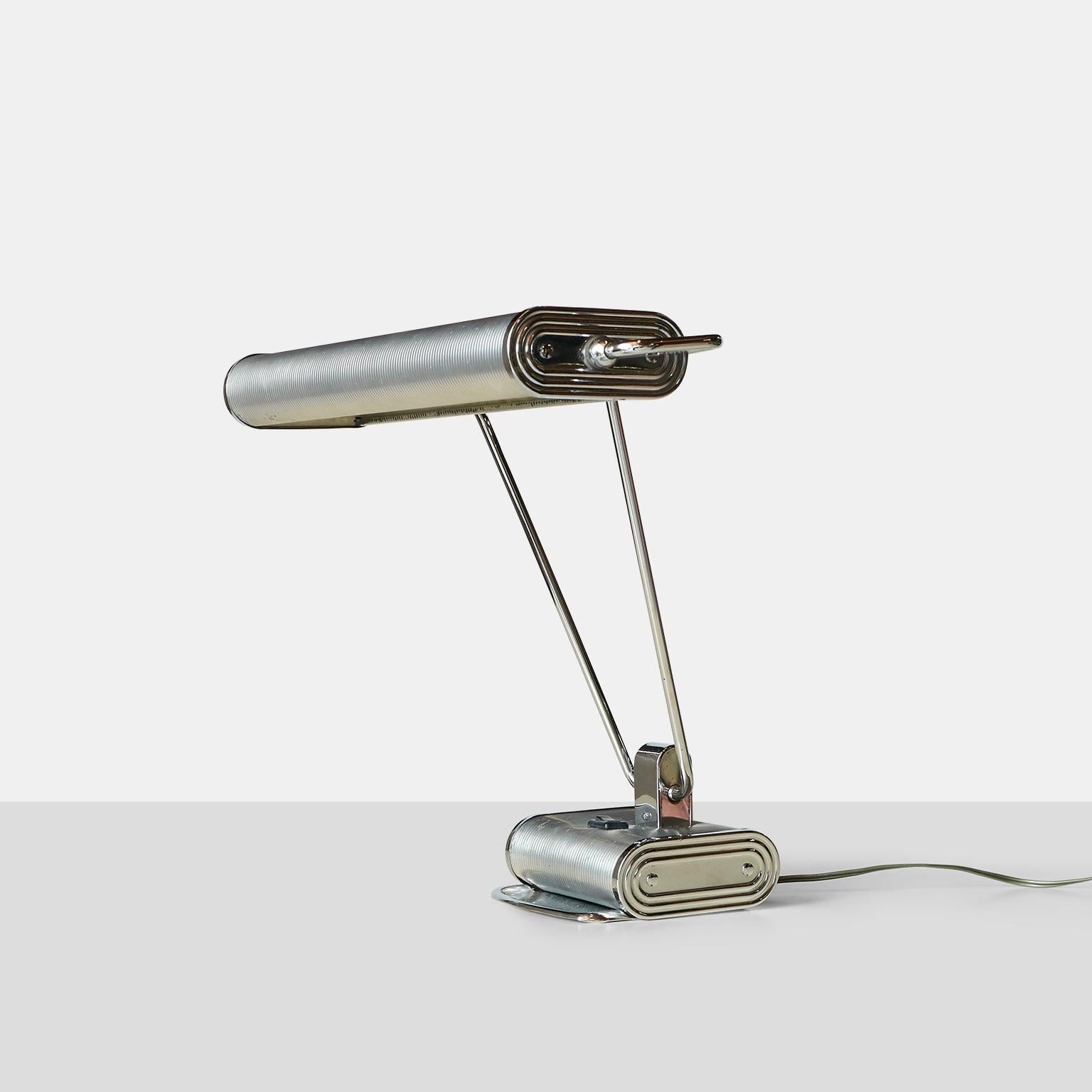 An desk lamp for the French manufacturer Jumo from the early 1940s. Attributed often to Eileen Gray  Adjustable arm and shade in silver lacquered metal and chrome. Two-light bayonet bulbs with the switch located on base.