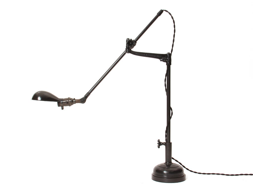 An adjustable swing-arm desk lamp with a cast iron base and a turtle shade. Manufactured by O.C. White Co. in the USA.