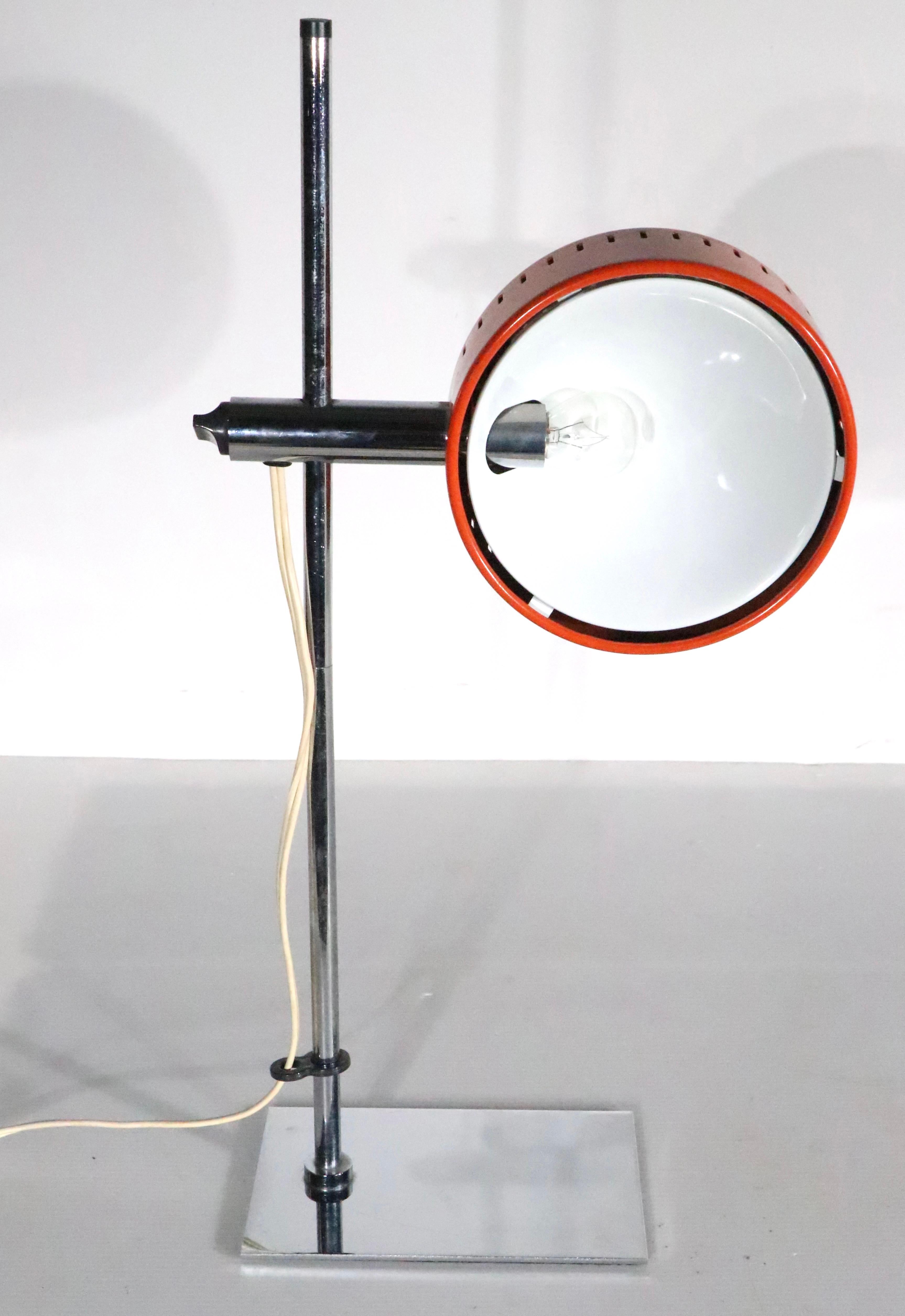 Very nice Post Modern adjustable desk lamp designed by Robert Sonneman for Nanbu-Lite, Made in Japan circa 1970's. The lamp features a disk form shade, in original orange paint finish, with a white interior,  which raises and lowers on the chrome