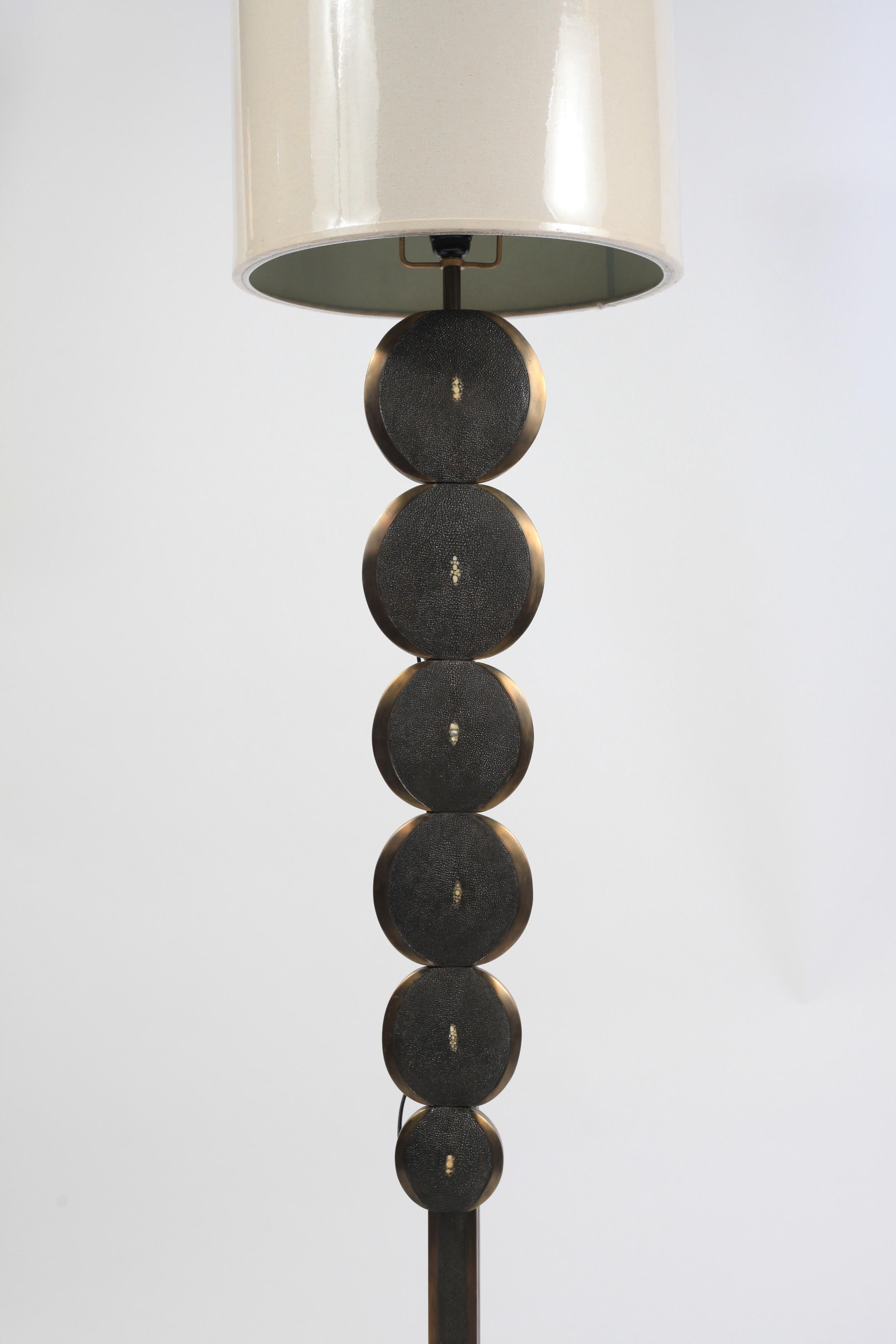 Ce lampadaire réglable en galuchat noir et laiton patiné bronze de R&Y Augousti est une pièce sculpturale avec de beaux détails d'incrustation. Ce lampadaire présente des parties circulaires qui augmentent progressivement et sont incrustées dans un