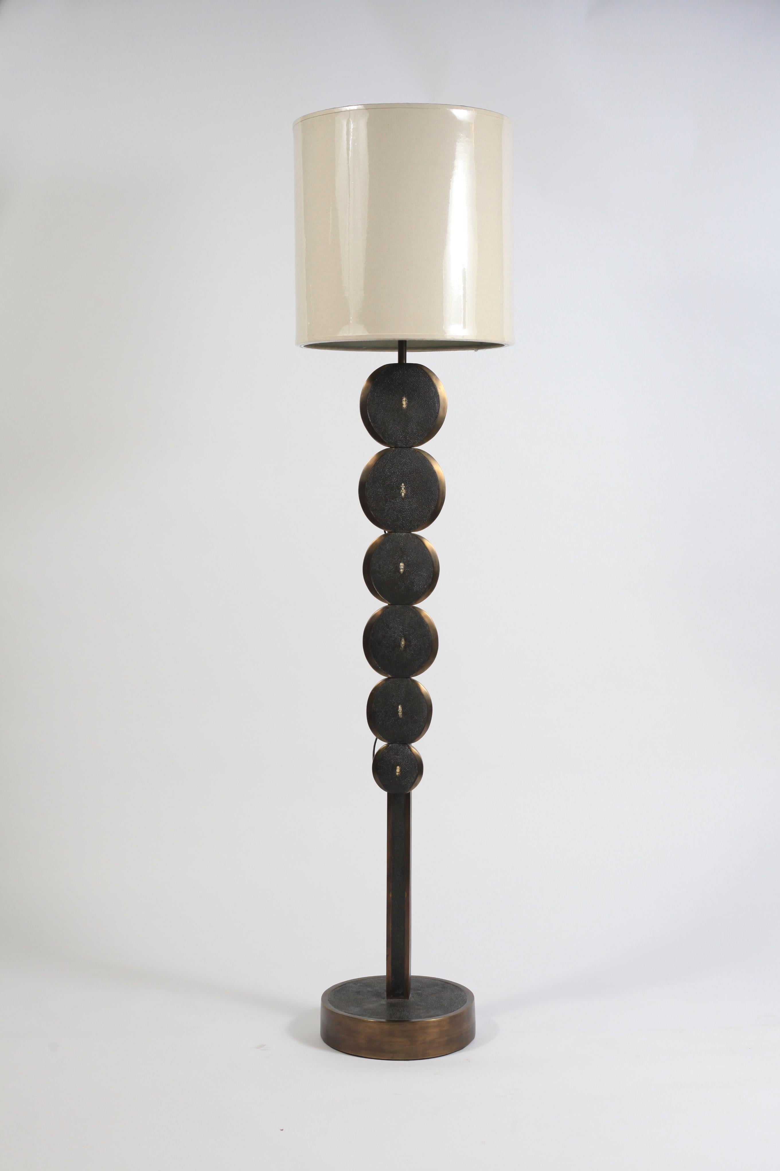 This adjustable floor lamp in cream shagreen and bronze patina brass by R & Y Augousti is a sculptural piece with beautiful inlay detailing. This floor lamp features circle parts that gradually increase and are inlaid with a bronze-patina brass