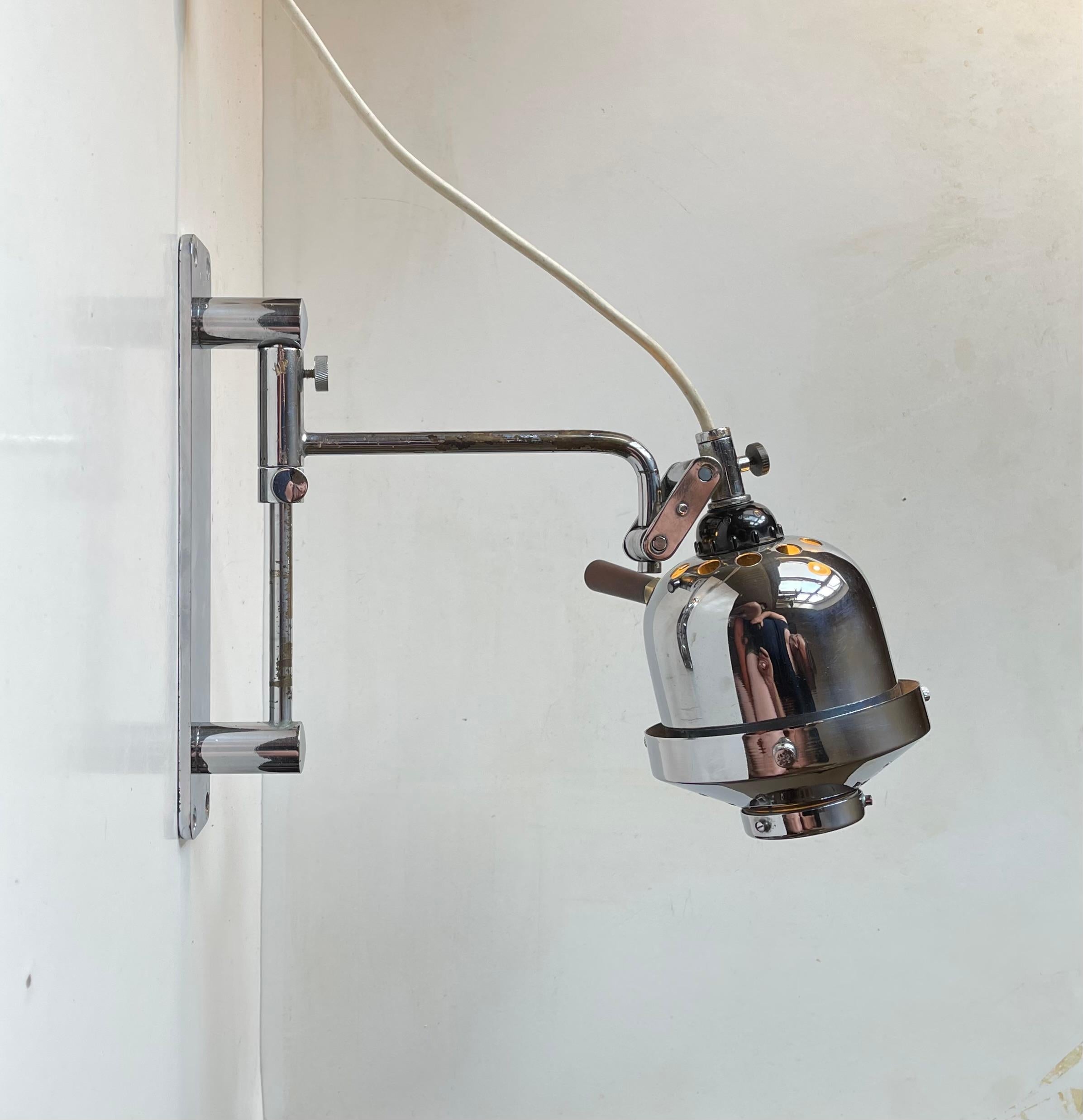 A very rare and seldom found medical fully adjustable wall sconce in chrome-plated brass. Its futuristic shade has a glass 'eye'/lens that softens and direct the light distribution. This particular example came from the estate of a retired