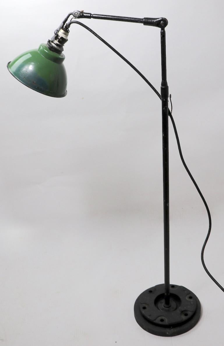 Adjustable floor lamp with green enamel shade, tubular iron arm and vertical rod. This example is in very good original and working condition, showing only cosmetic wear normal and consistent with age. The green enamel shade has been overpainted in
