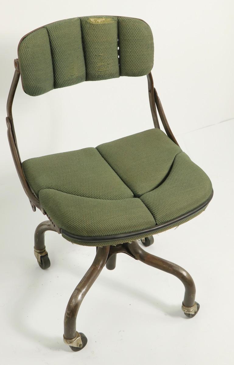 Adjustable Industrial task chair manufactured by DoMore. The chair is adjustable in height, and the backrest tilts as well. The upholstered seat revolves on the tubular legs, which have their original rolling caster feet. Great example of early