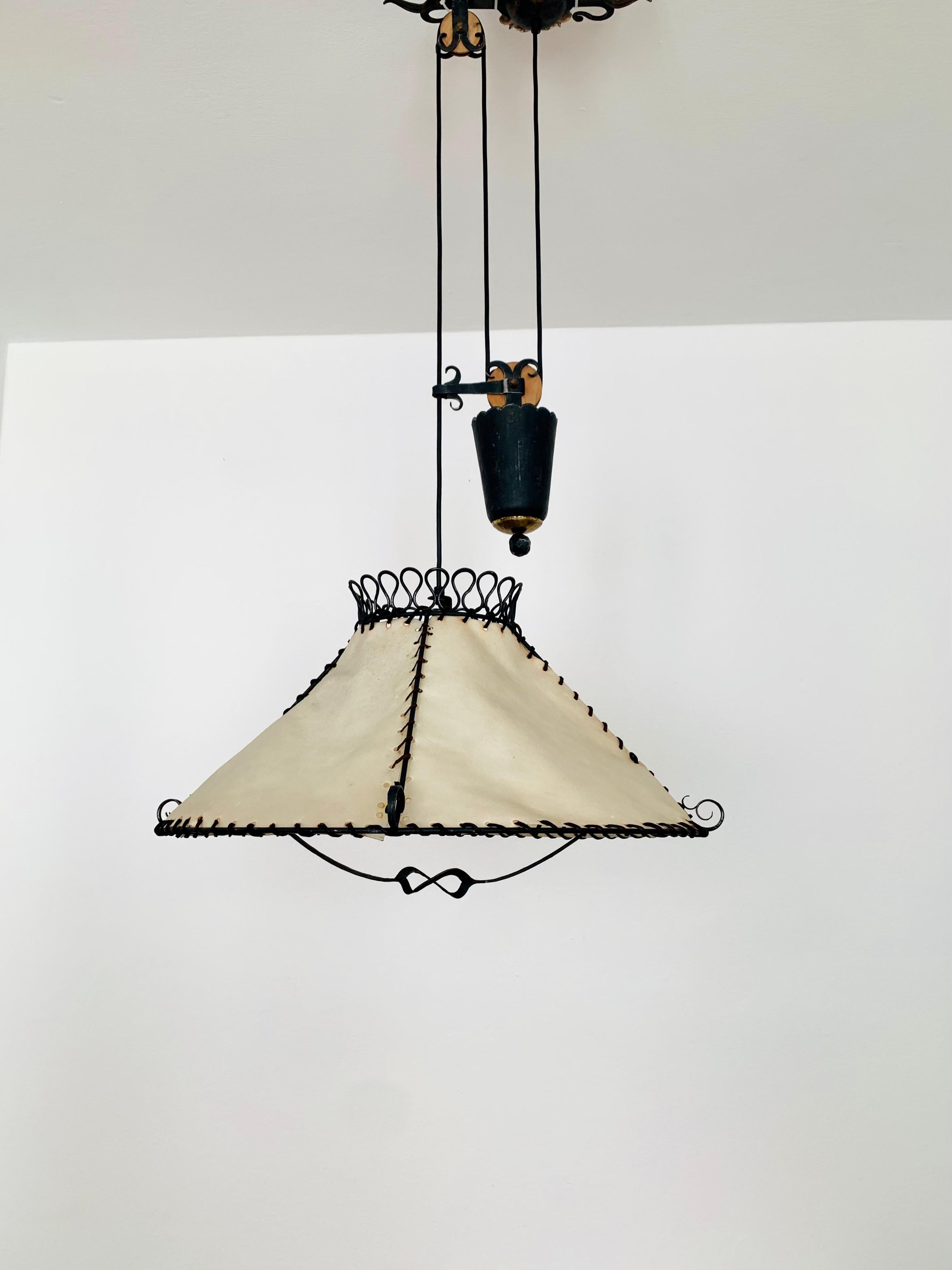 Exceptional height -adjustable pendant lamp from the 1950s.
High quality and detailed workmanship.
The leather creates a cozy light.

Condition:

Very good vintage condition with slight signs of wear.
Very nice patina on the iron.
The leather straps