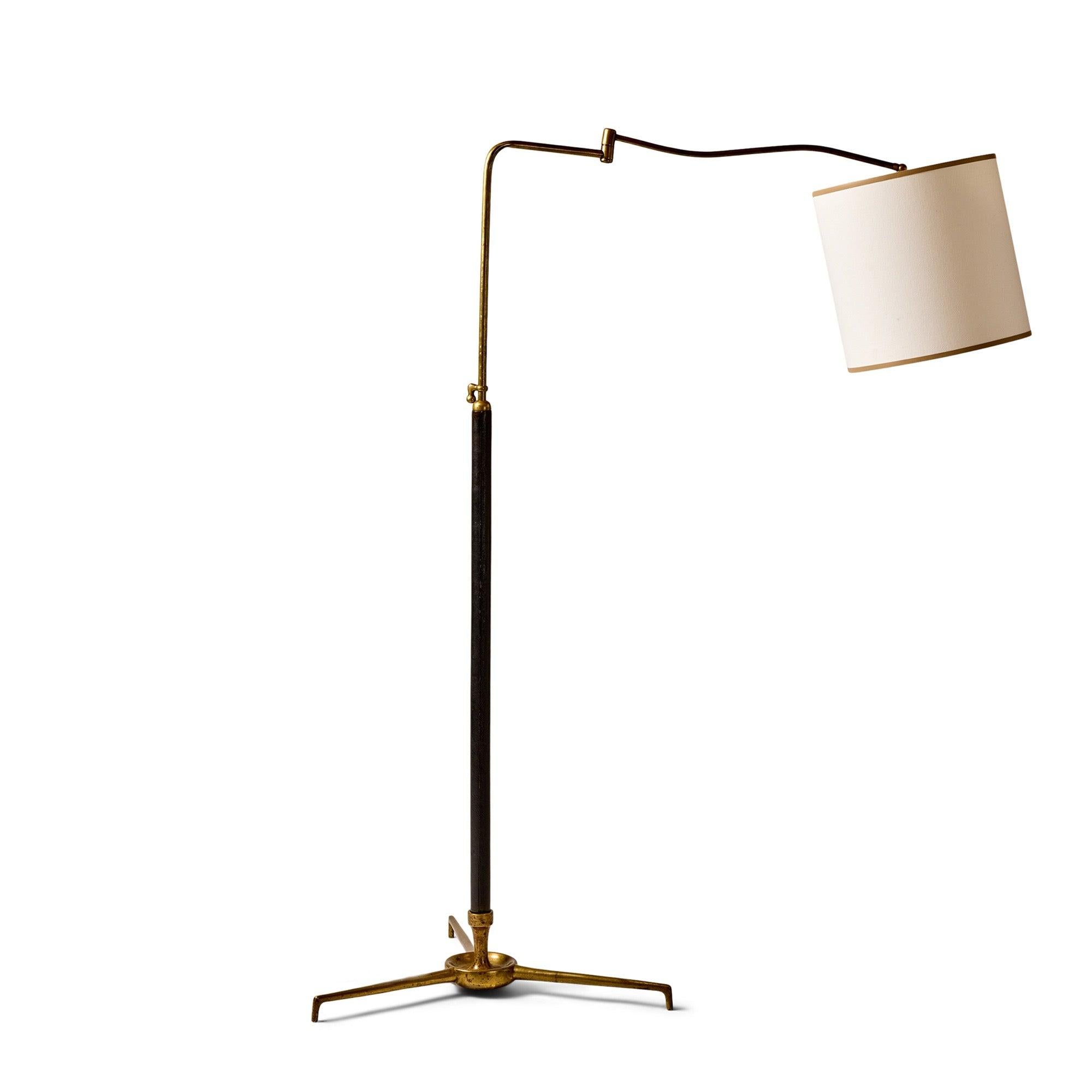 Una lampada da terra a braccio oscillante con base a treppiede in bronzo patinato e stelo avvolto in pelle.
