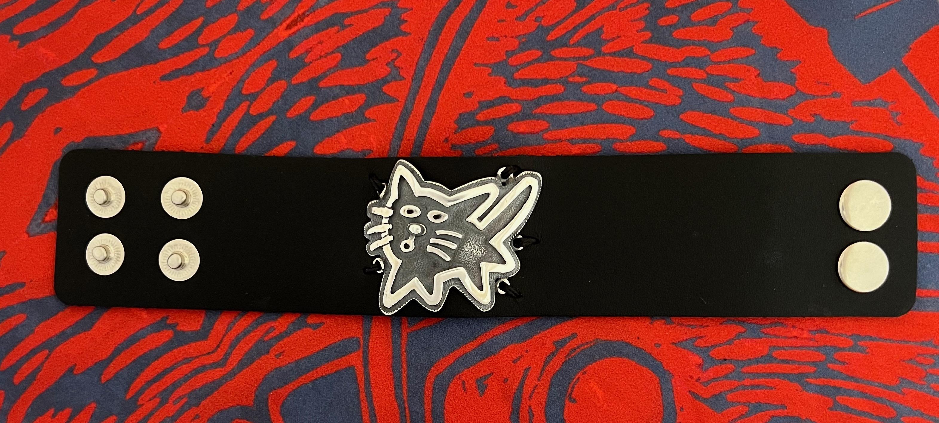Adjustable Kitty leather cuff by Melanie Yazzie, black leather, Sterling Silver

Melanie A. Yazzie (Navajo-Diné) is a highly regarded multimedia artist known for her printmaking, paintings, sculpture, and jewelry designs. She has exhibited,