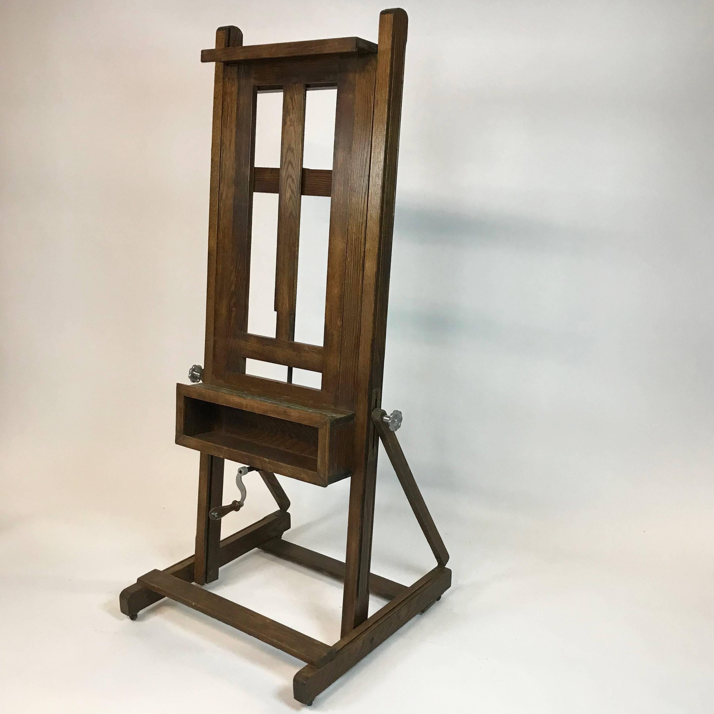 Large format, oak, full frame, fully adjustable, studio artists easel raised up on a trestle base with all original hardware The front crank tilts the easel up to 15 degrees from vertical. The easel opens up to fit a frame up to 39 inches wide and