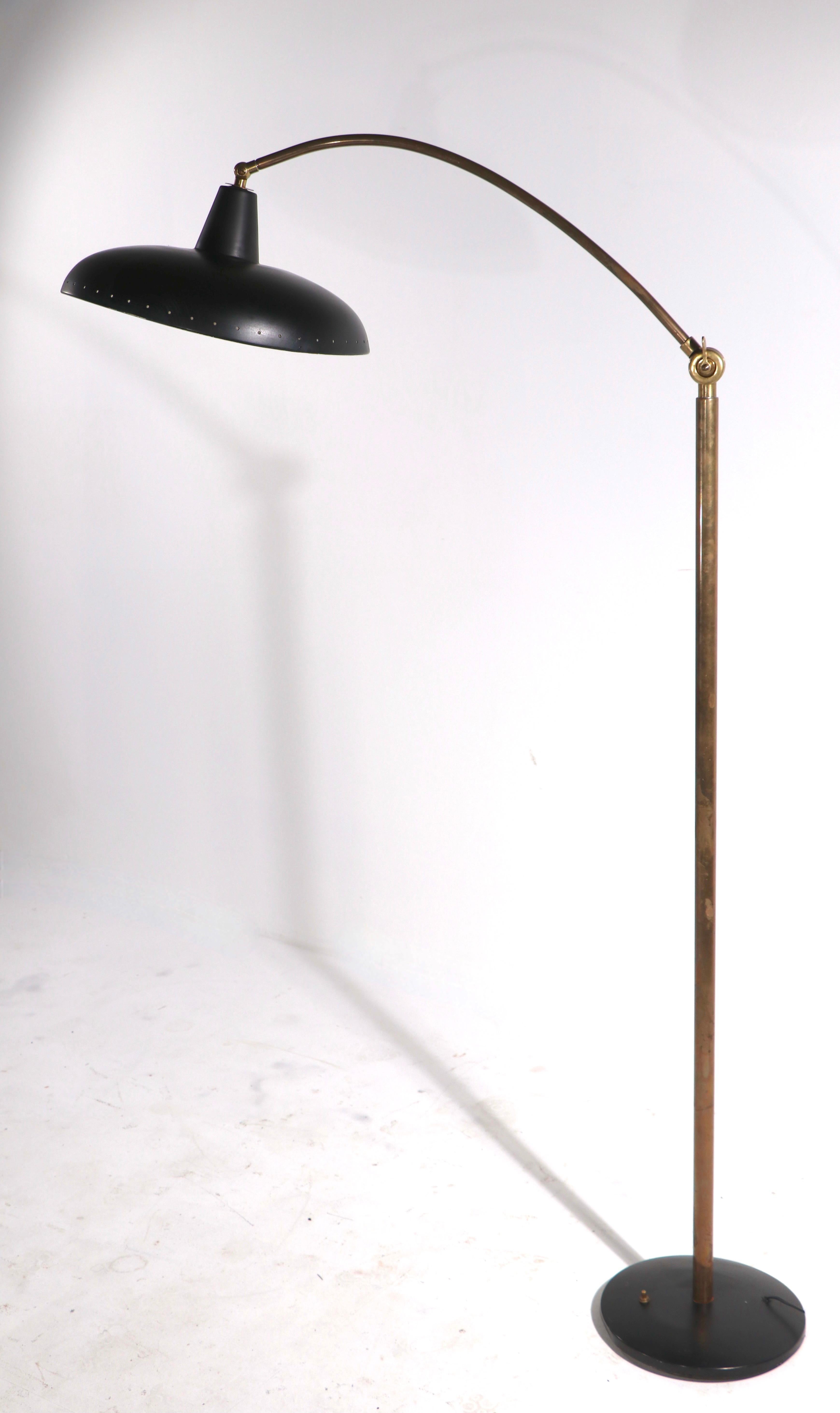 Well crafted mid century floor, reading lamp with black hood shade, and black base, with a brass vertical standard and arm. The lamp is adjustable in height ( L 48 in. H 67 in. ) the hood shade ( 13 in Dia ) tilts, to position the light exactly