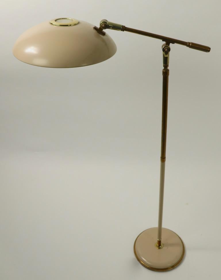 Chic mid century floor lamp designed by Gerald Thurston for Lightolier. The lamp adjusts in height from lowest position 42 inch to highest position 53 inch, the saucer disk shade (12 in. diameter) tilts and pivots, and the arm tilts to direct the