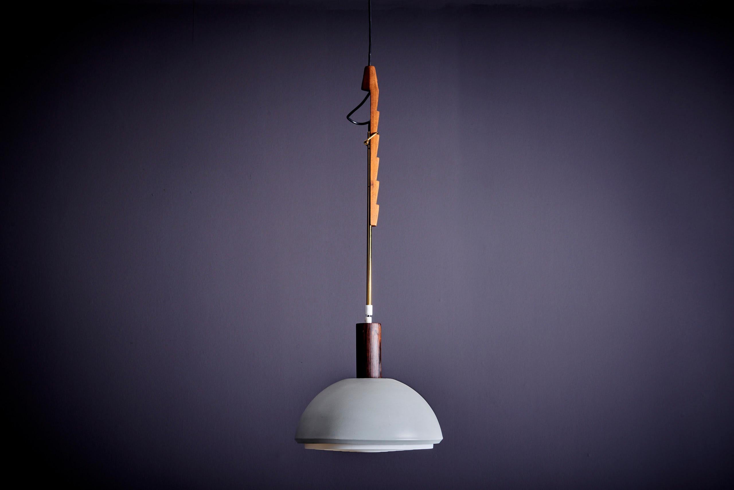 Lampada a sospensione regolabile in altezza, progettata da Svend Aage Holm Sørensen e prodotta da Holm Sørensen and Co in Danimarca. Realizzato in legno di teak, ottone, metallo e plastica.

1 presa E27.

Nota bene: il montaggio della lampada