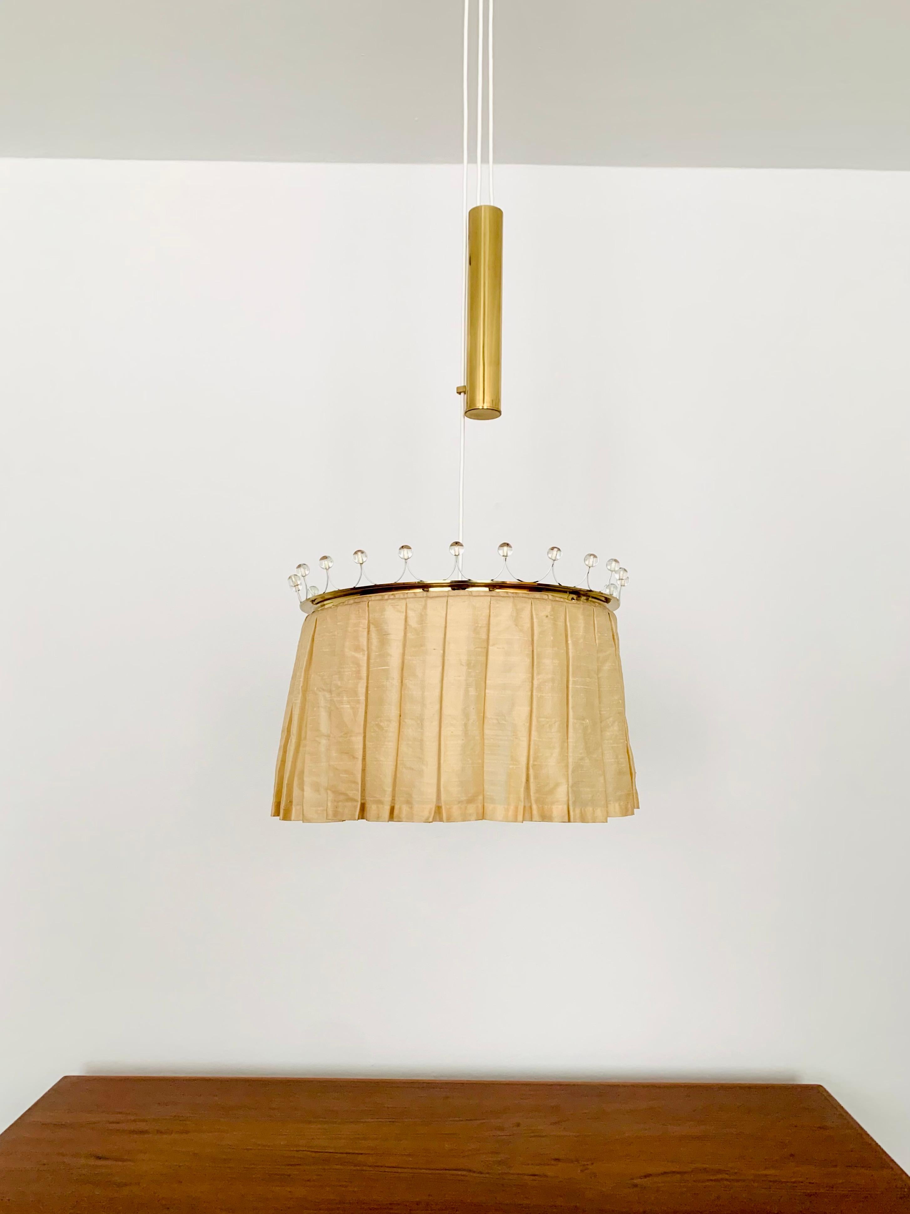 Very rare height-adjustable pendant lamp from the 1950s.
High-quality materials such as silk, brass and crystal glass make the lamp a special design object.
A very cozy light is created.

Manufacturer: Vereinigte Werkstätten