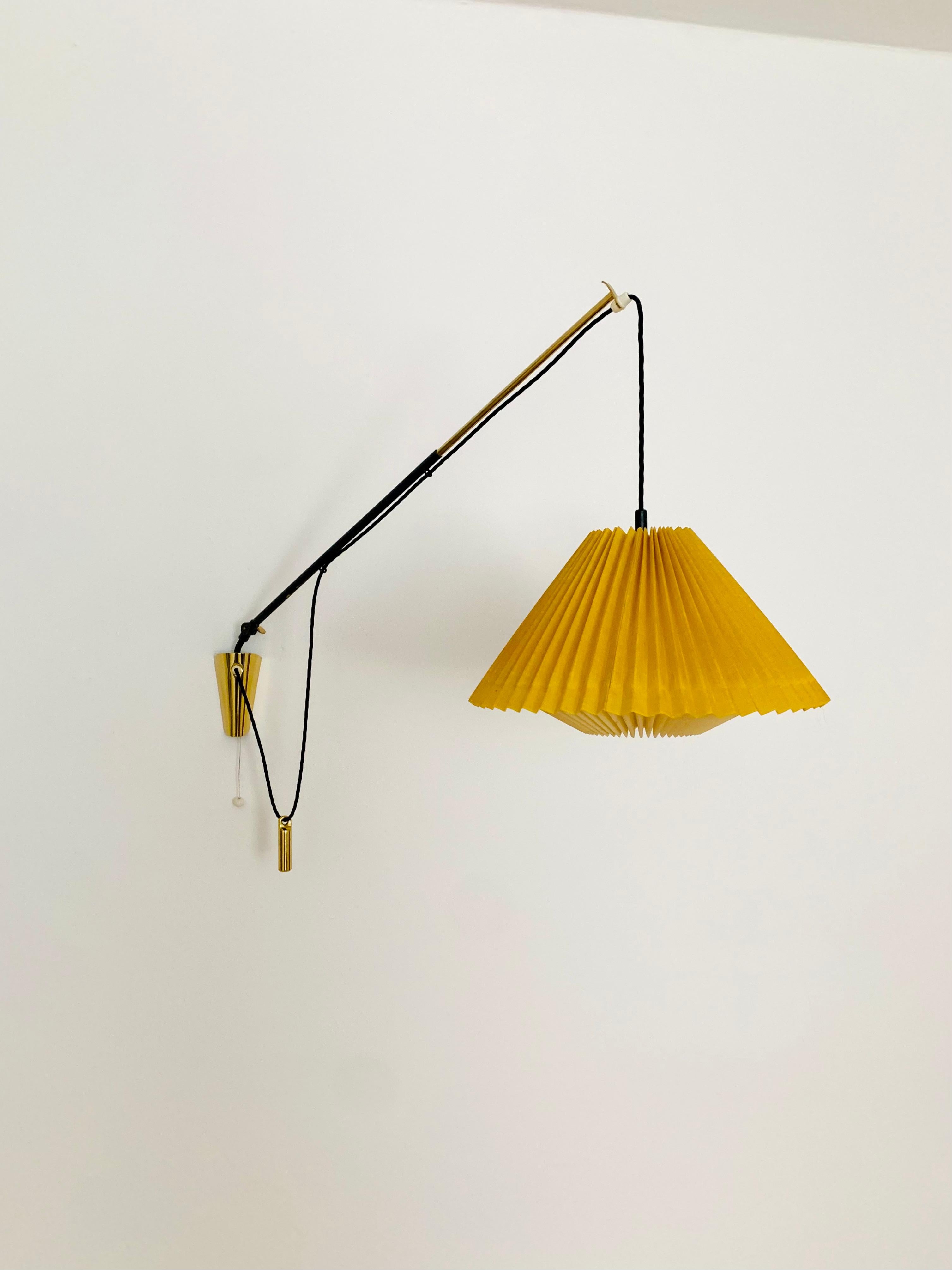 Charming adjustable wall lamp from the 1950s.
Great and exceptionally minimalistic design with a fantastically elegant look.
Very nice swiveling and extendable brass arm.
The pleated lampshade creates a wonderful play of light and a very cozy