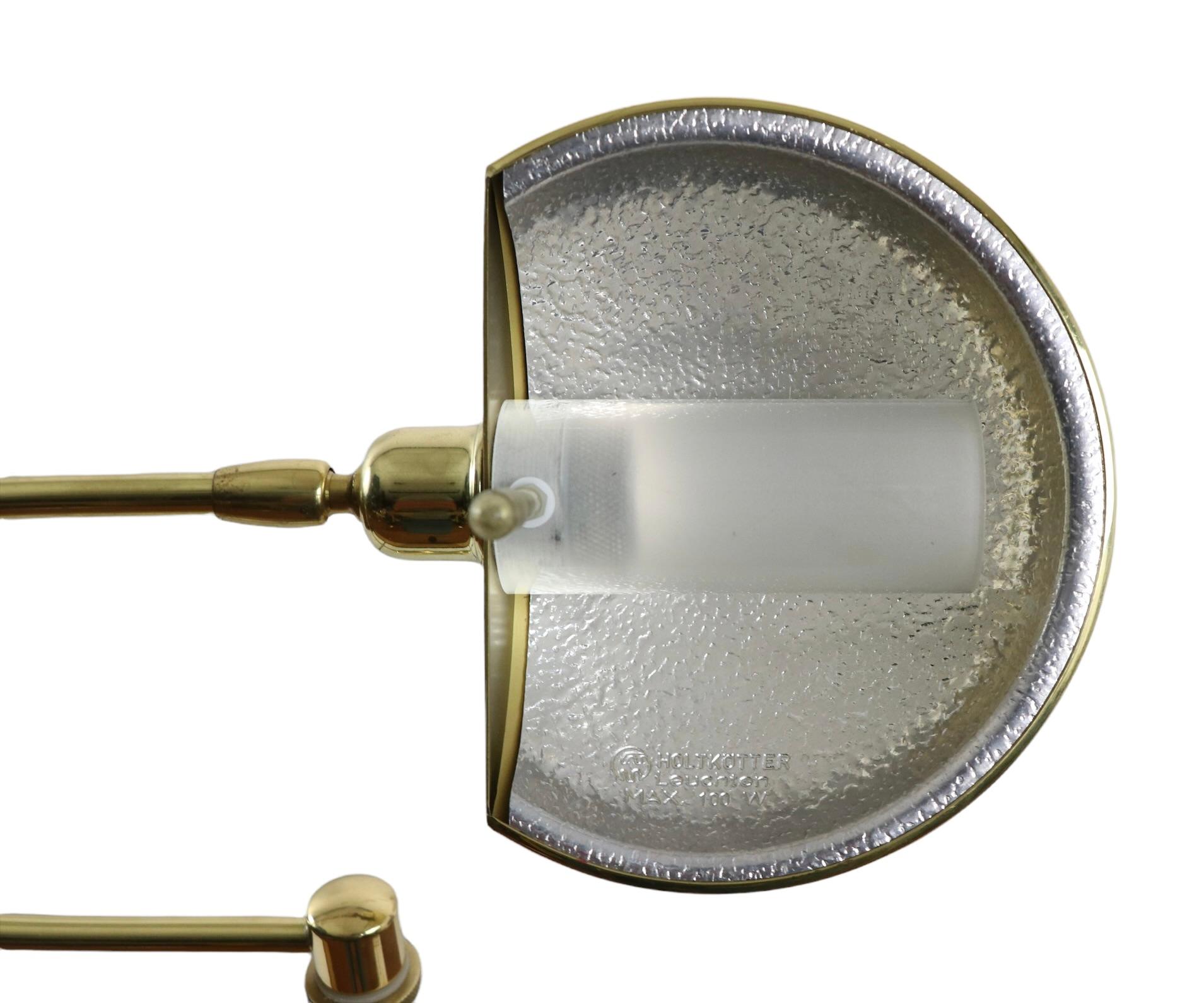 Exceptional brass pharmacy style floor lamp, Made in Germany by Holtkotter, circa 1980's. The lamp features a horizontal flex arm with stylized joinery, which swivels on the vertical post. the arm swivels and the hood shade tilts to position and
