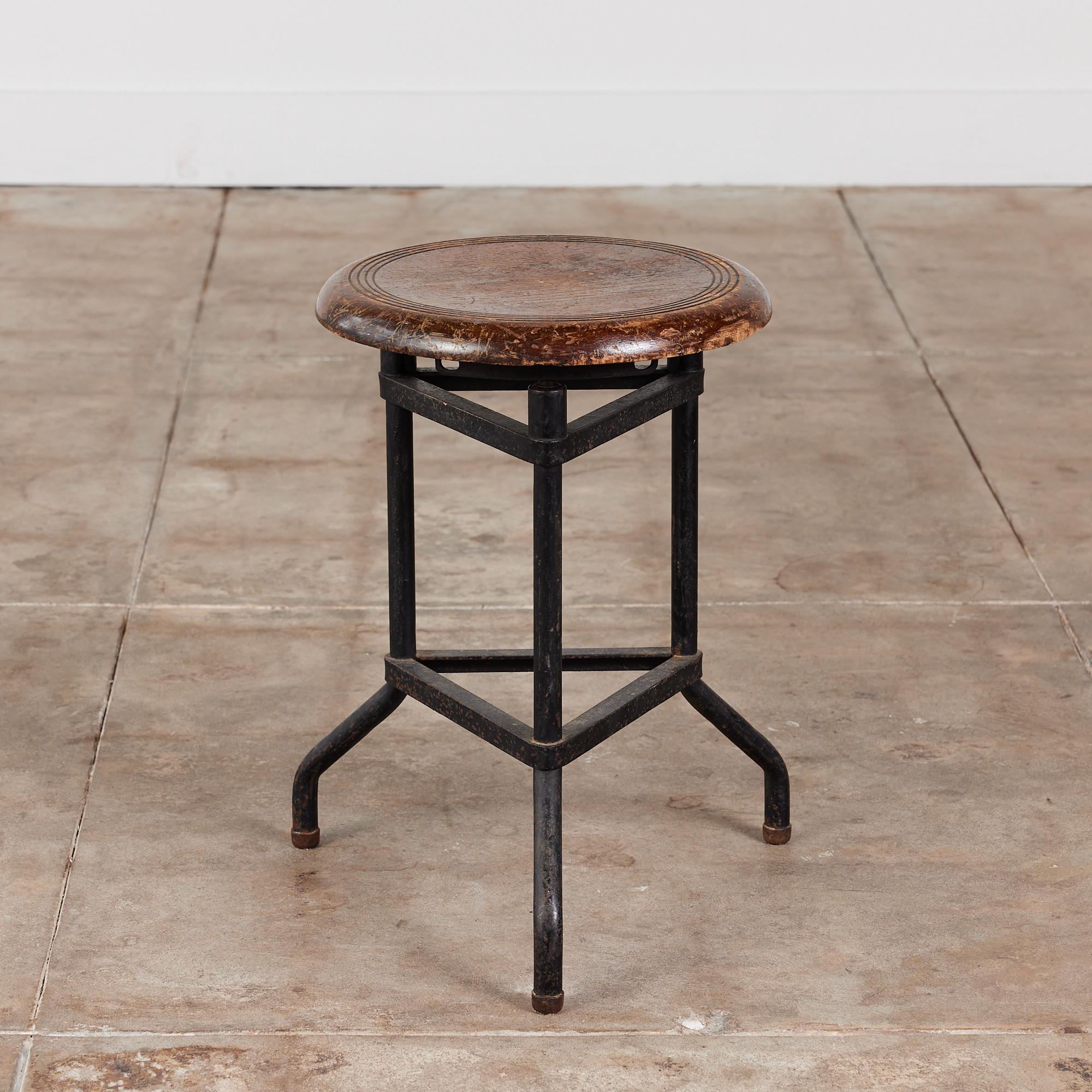 Adjustable stool by Campbell Corporation, circa 1990s, Rockford, Illinois. This industrial stool was used at the Campbell Corporation Headquarters Biotech Labs. The stool features a round wood seat and patinated tripod metal base. The seat height is