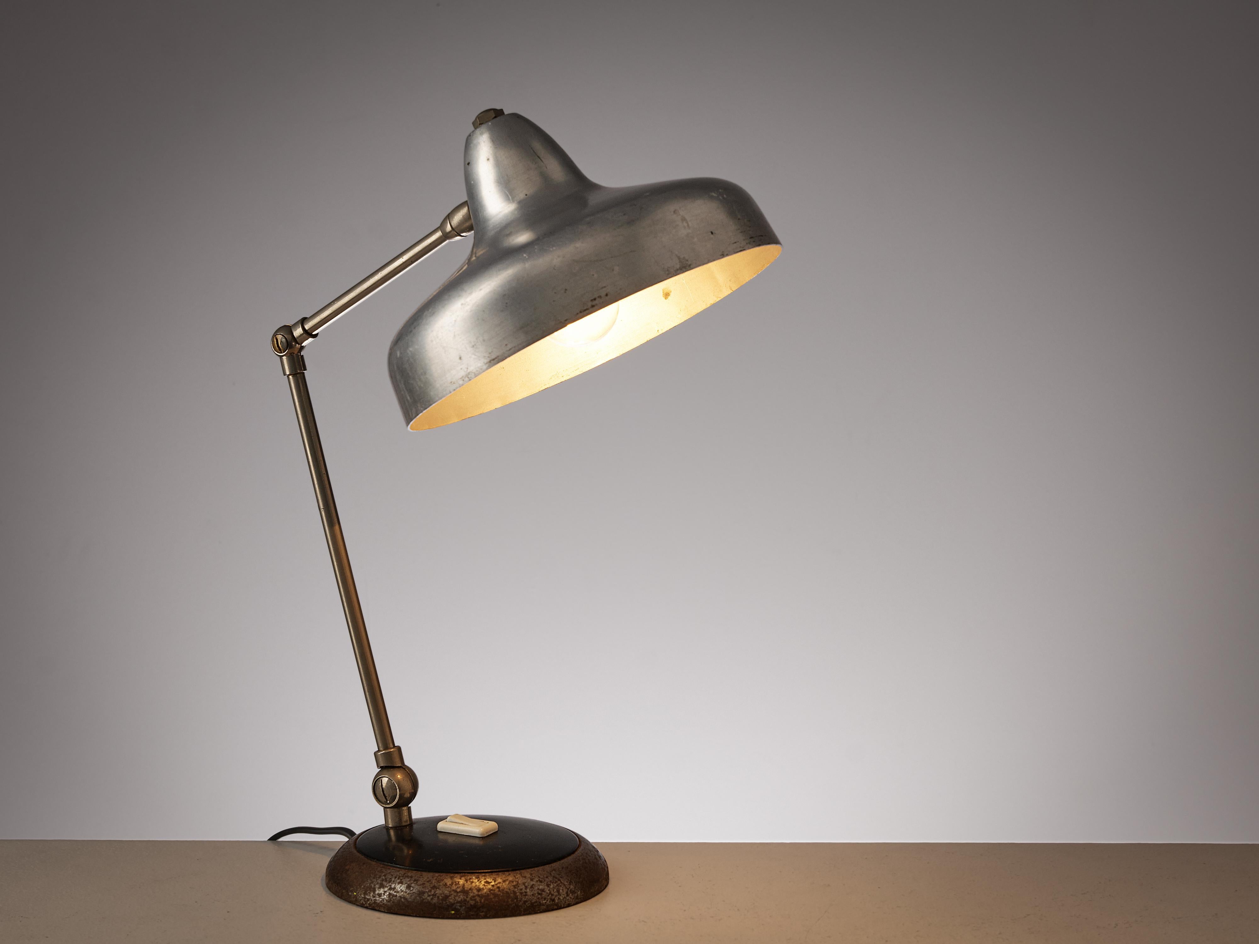 Table lamp, iron, aluminum, Europe, 1950s

This small table lamp combines functionality and visual pleasing design. From a round base in iron the adjustable stem with two arms is attached. At its end sits a silver, beautifully shaped lampshade