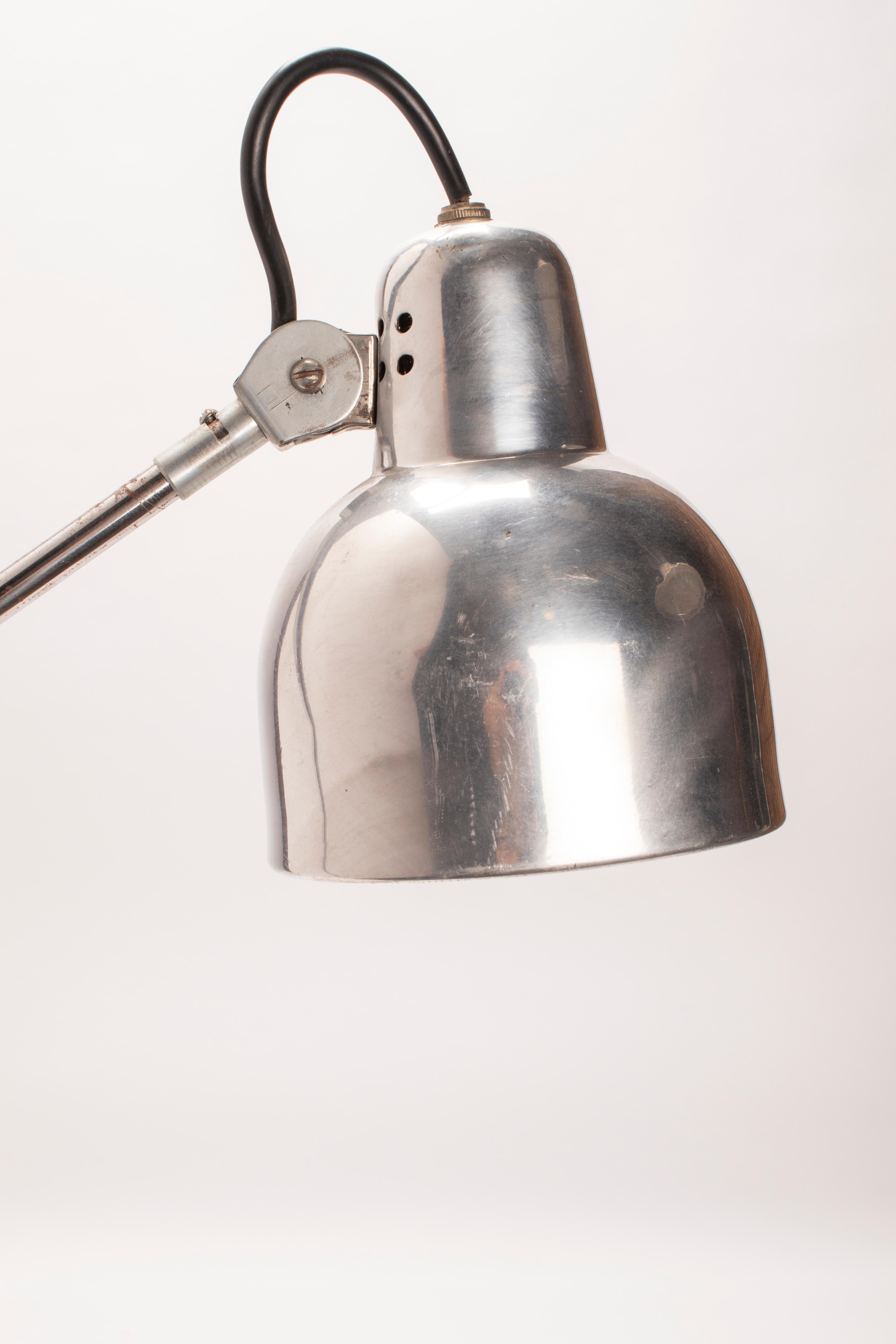Adjustable aluminum table lamp, articulated on three points. It can be anchored to a table or desk with a clamp. Equipped with a conical-shaped lampshade (7” x 5.5”). Re-electrified. France, circa 1930.