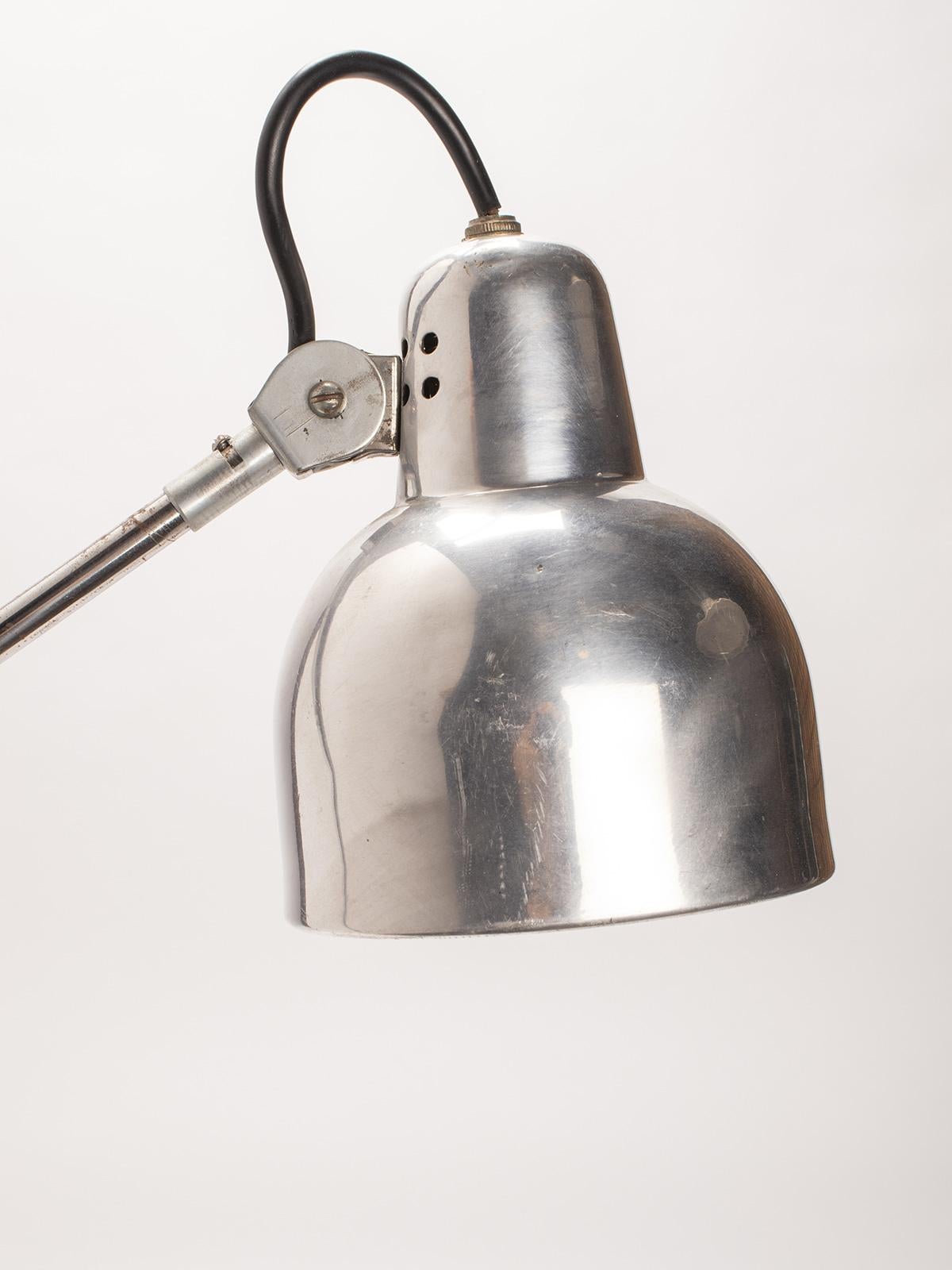 Adjustable aluminum table lamp, articulated on three points. It can be anchored to a table or desk with a clamp. Equipped with a conical shaped lampshade (7” x 5,5”). Re-electrified. France circa 1930.

