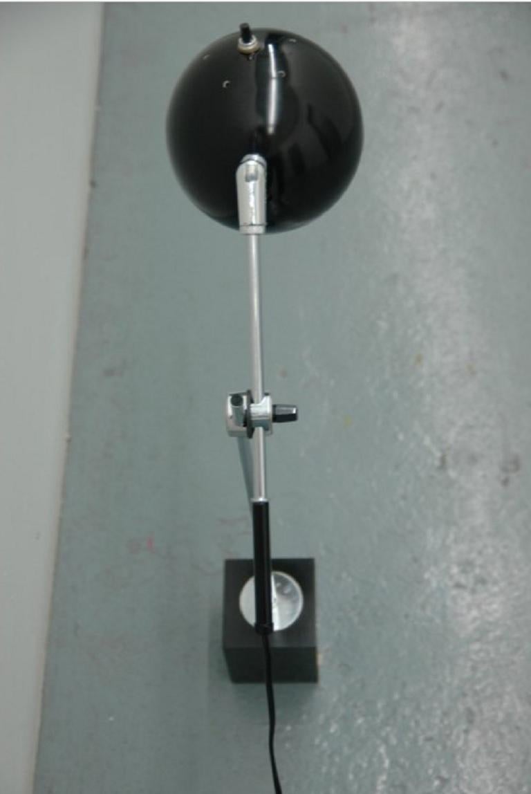 Une paire de lampes avec une base rectangulaire noire avec des bras pivotants se terminant par une tête de globe noir laqué avec un contrepoids noir à l'autre extrémité - convenant bien comme lampe de bureau ou lampe de chevet.